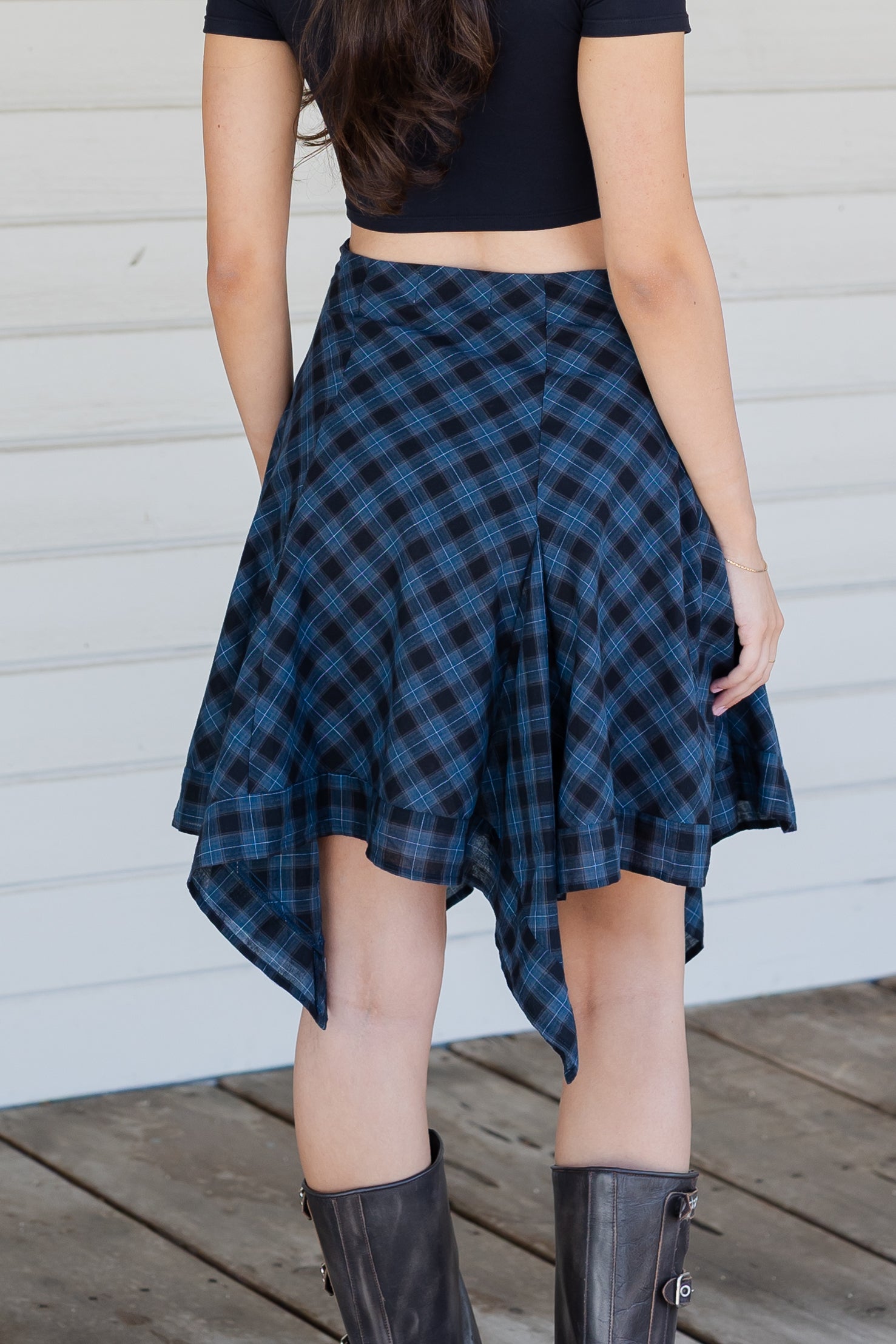 Person wearing a blue plaid skirt with a plain background