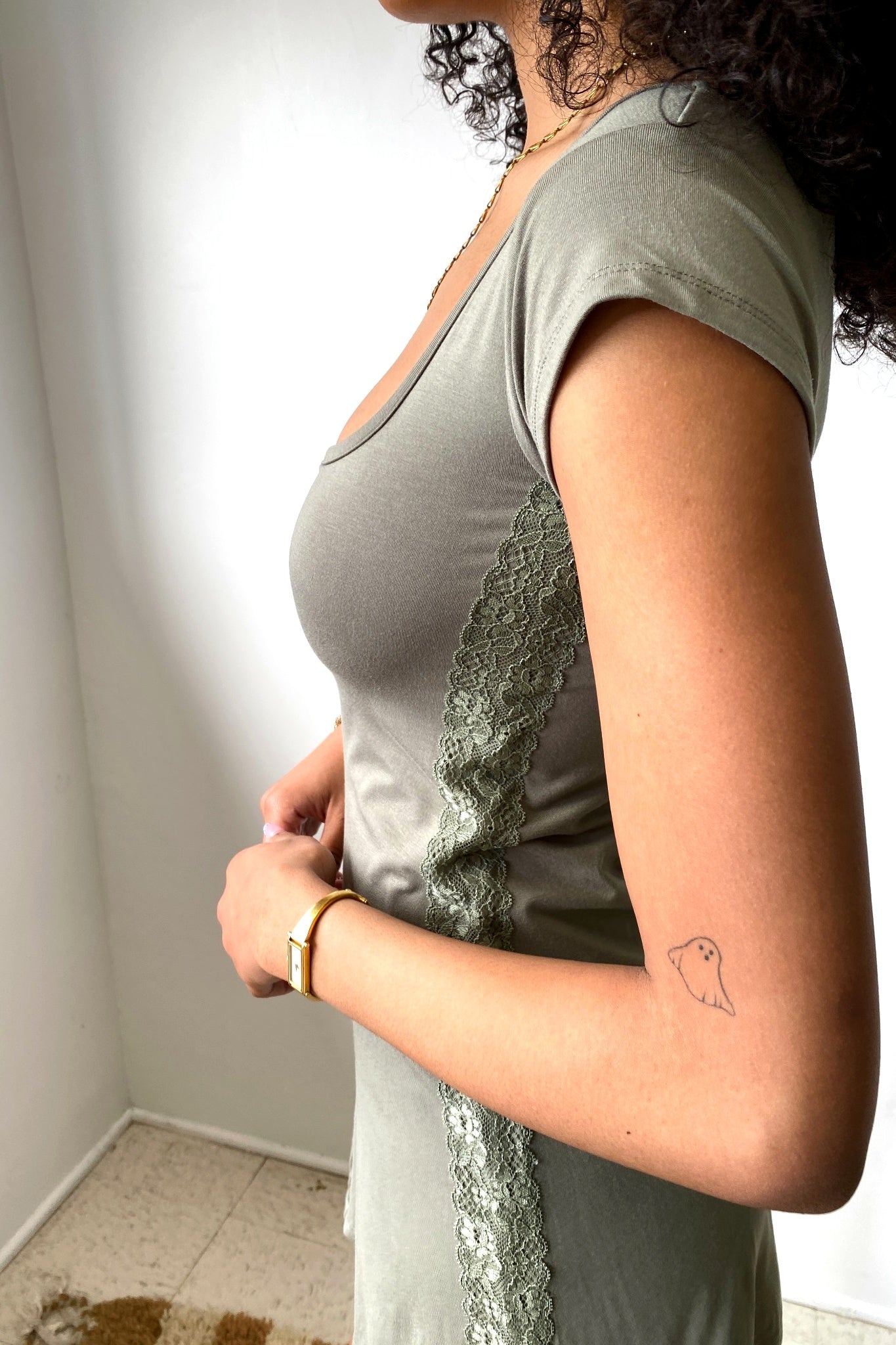 Woman wearing a green dress with lace details, standing against a plain background.