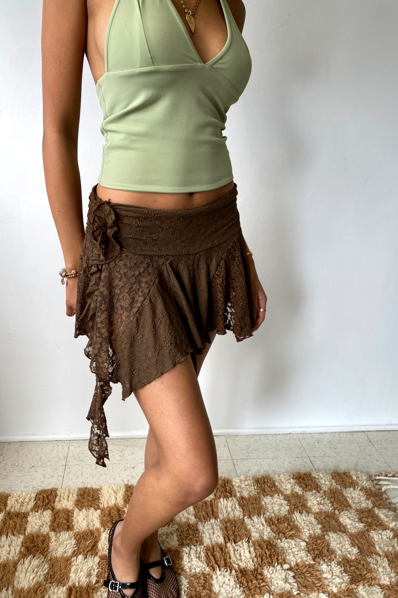 Person wearing a green top and brown skirt on a plain background