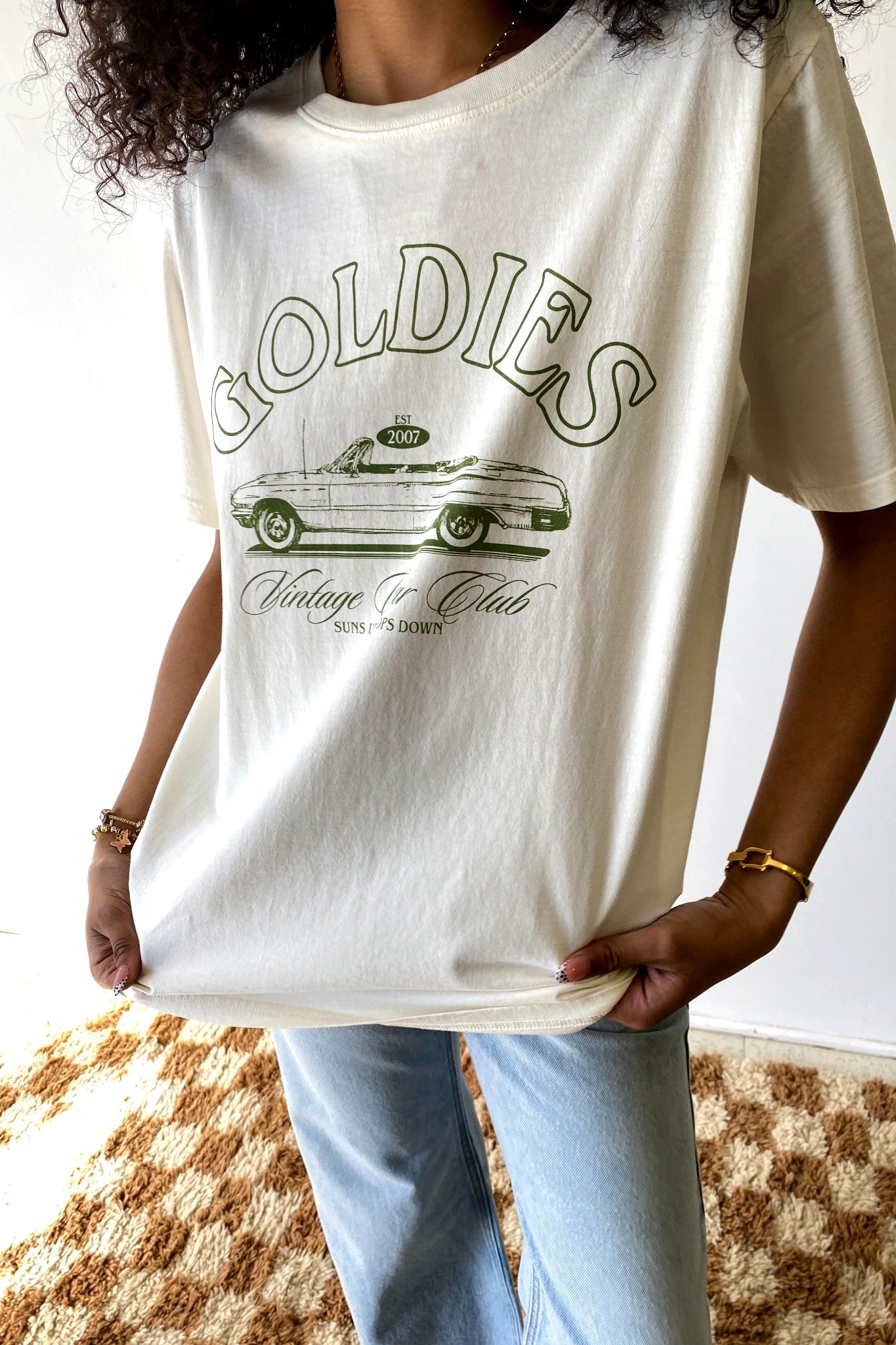 Person wearing a white t-shirt with 'Goldies' graphic design.