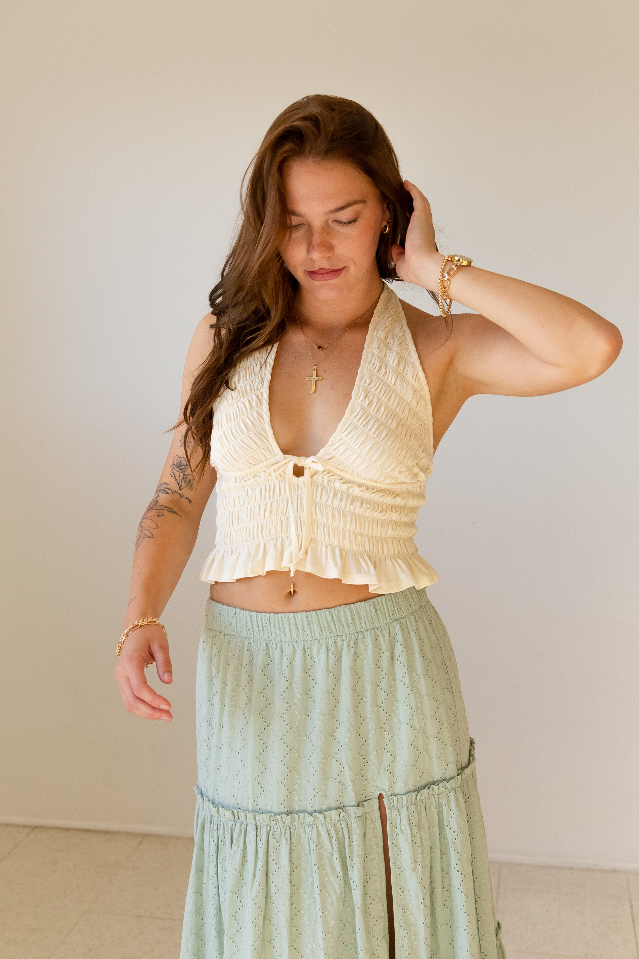 Woman wearing a beige top and light green skirt against a plain background