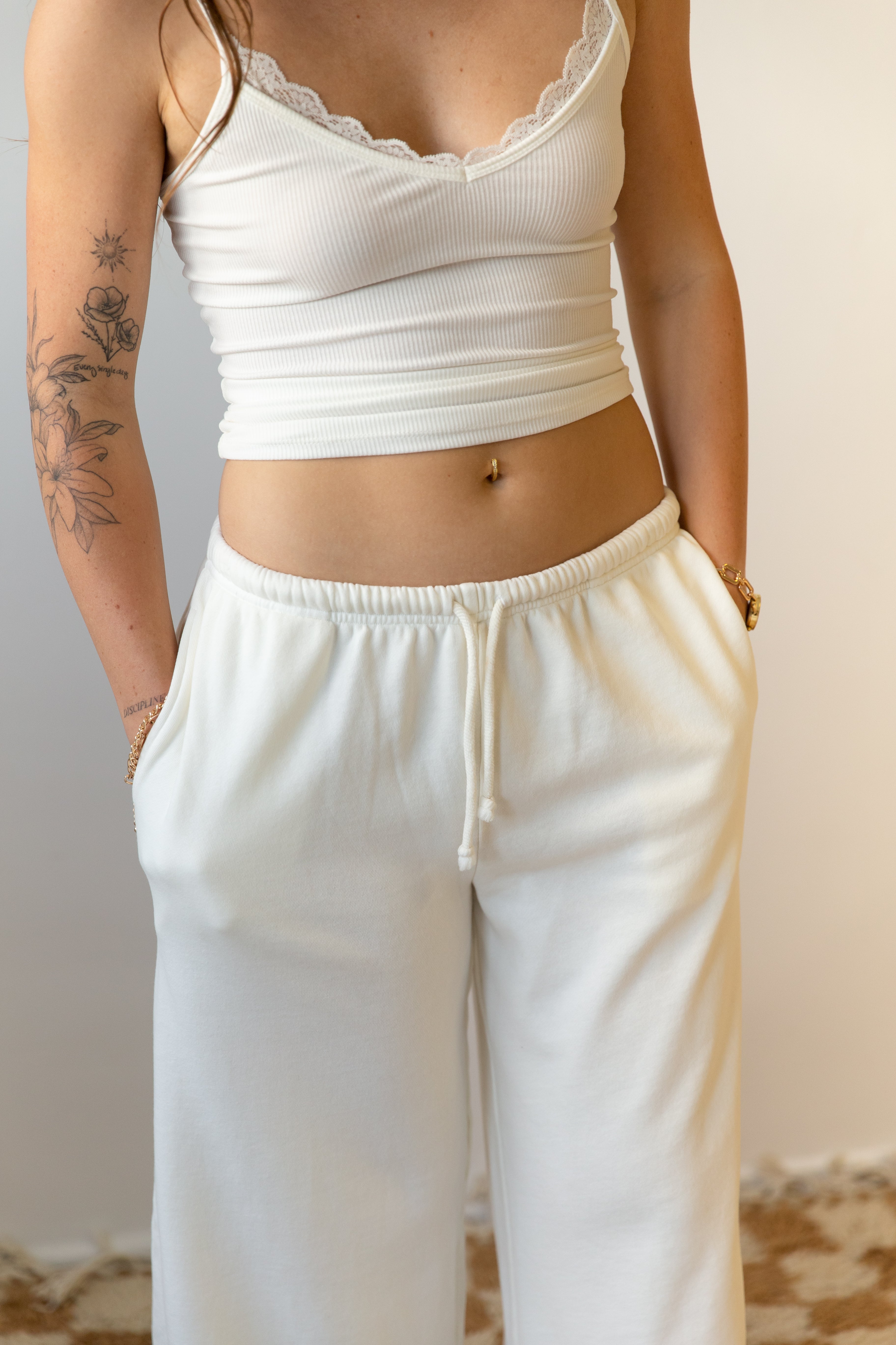 Person wearing a white crop top and pants against a neutral background
