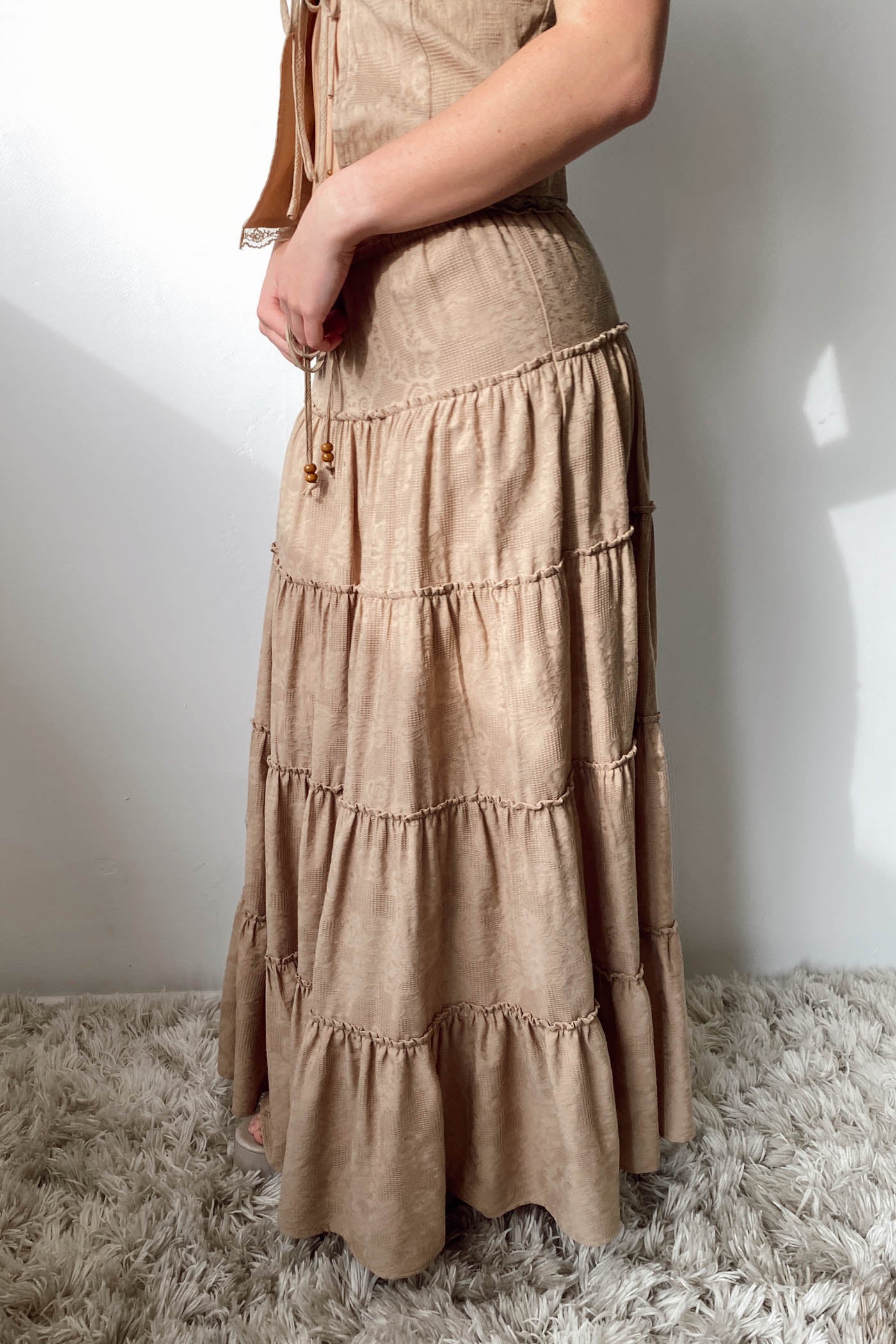Beige tiered dress worn by a person on a white background