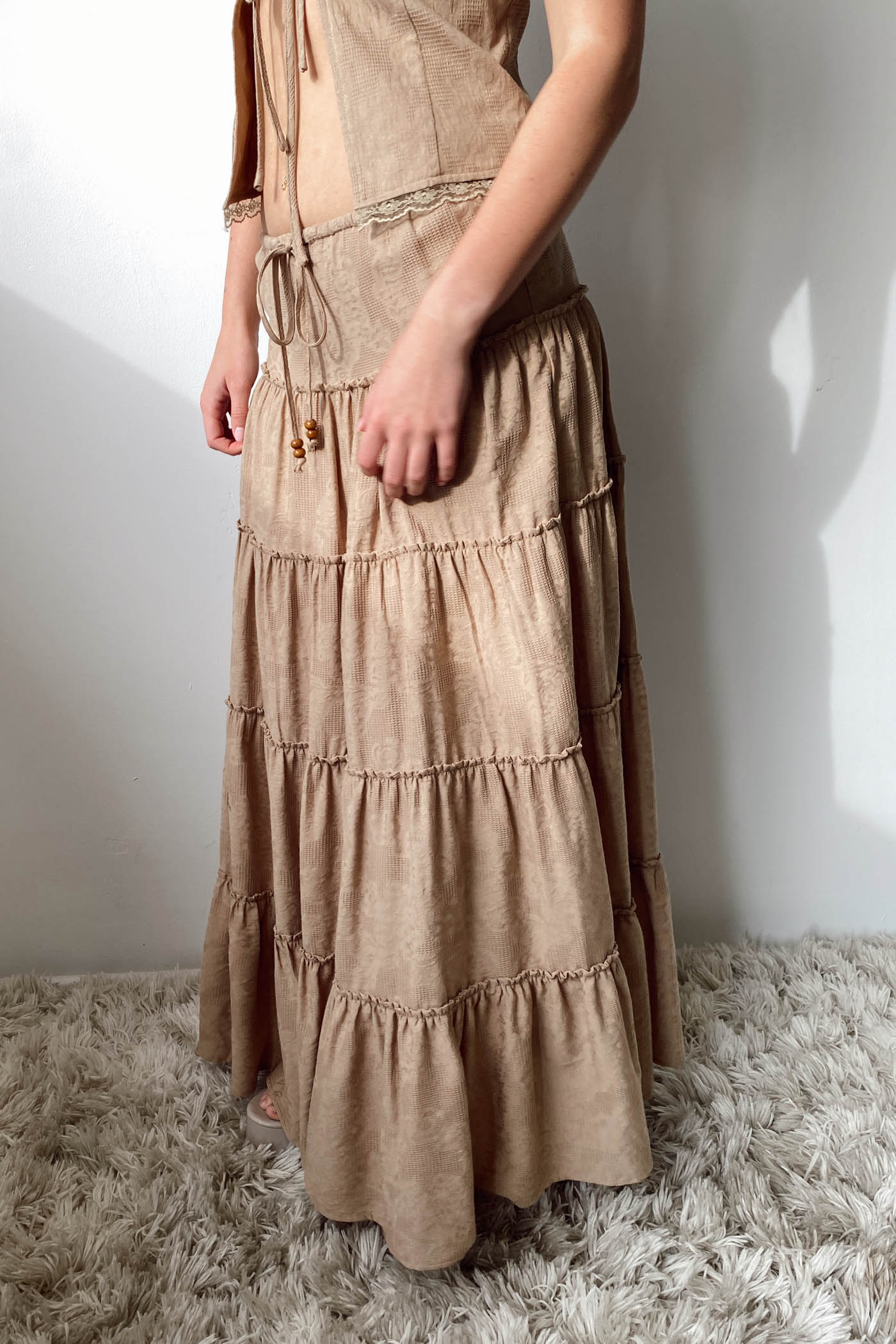 Long beige dress with tiered layers on a white background