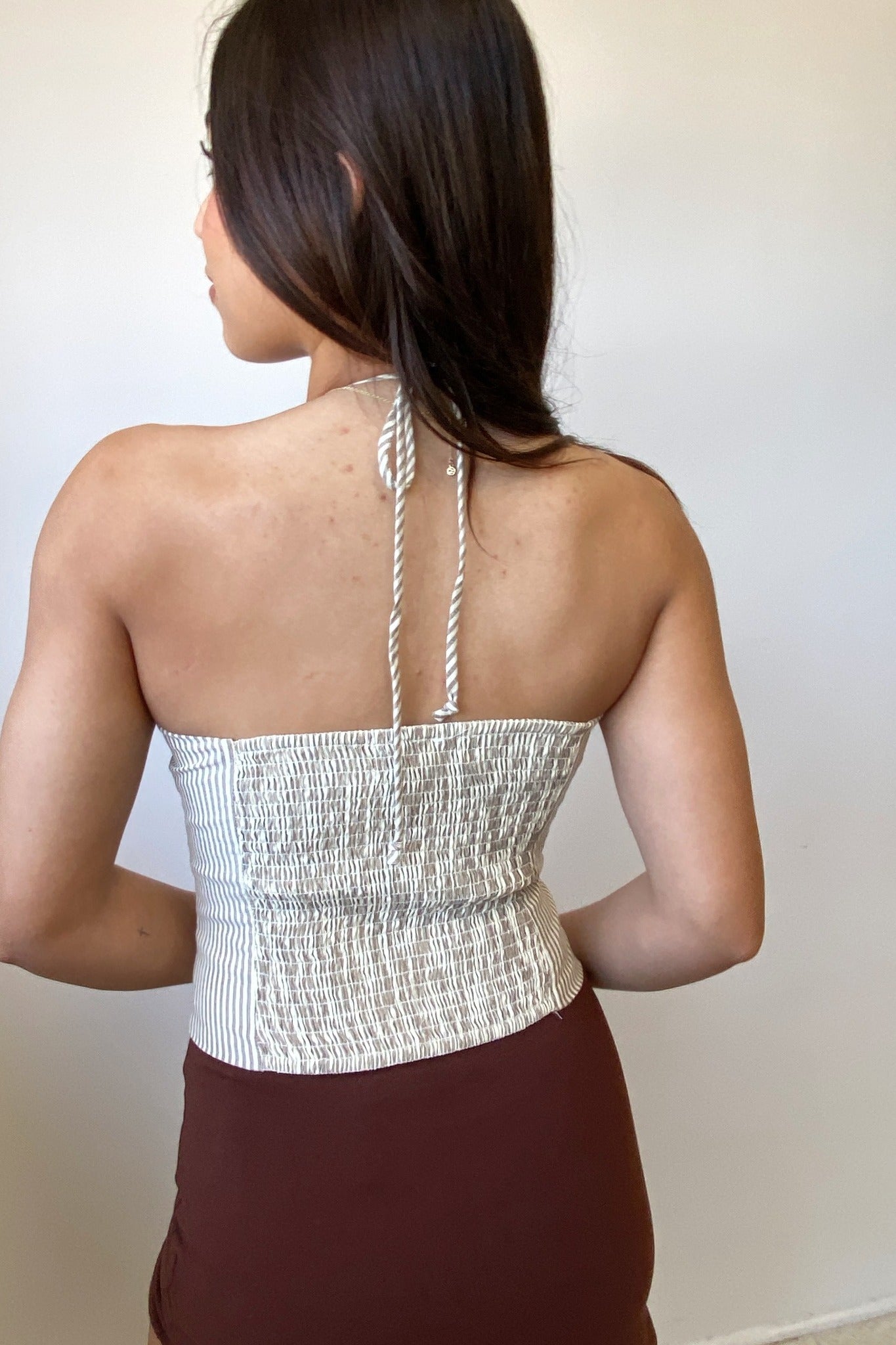 Woman wearing a white strapless top with a textured pattern against a plain background