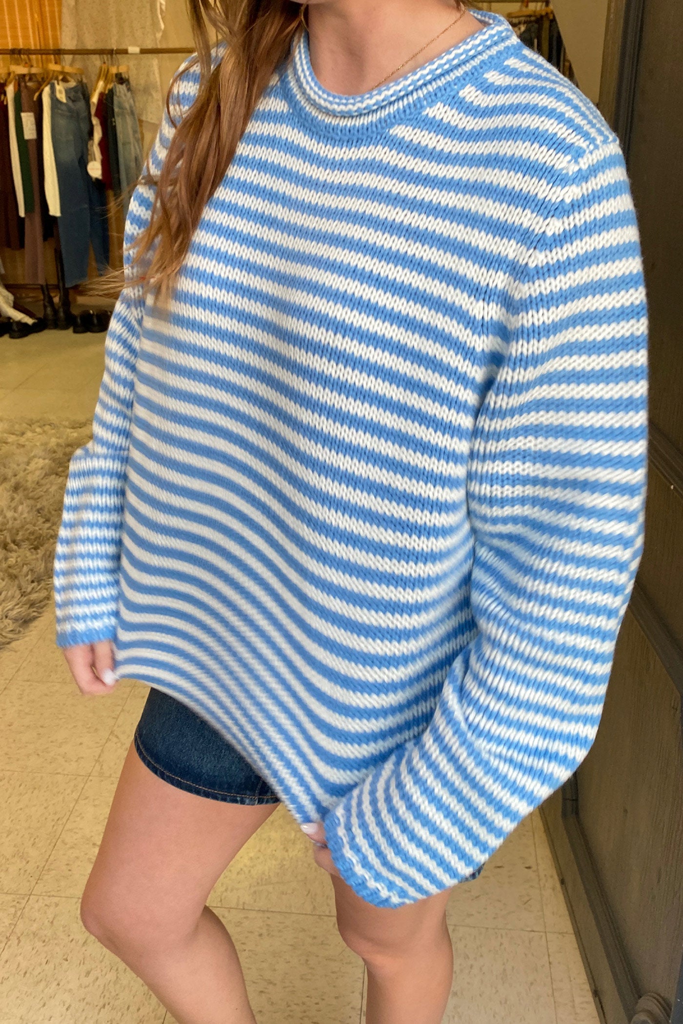 Person wearing a blue and white striped sweater in a clothing store.