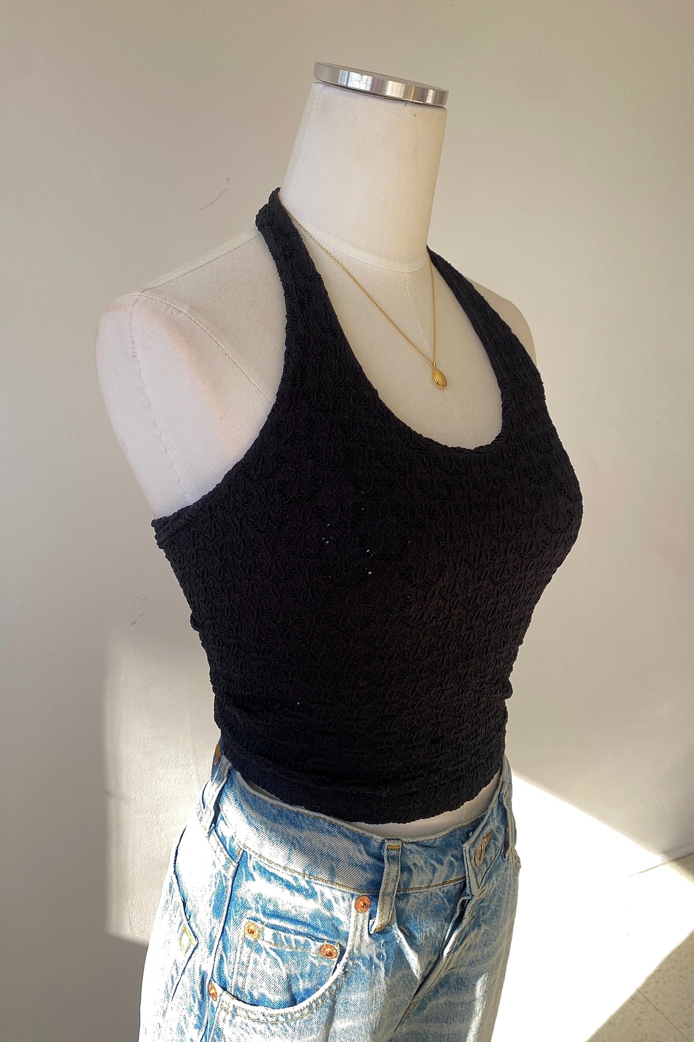 Mannequin wearing a black tank top and light blue jeans against a neutral background