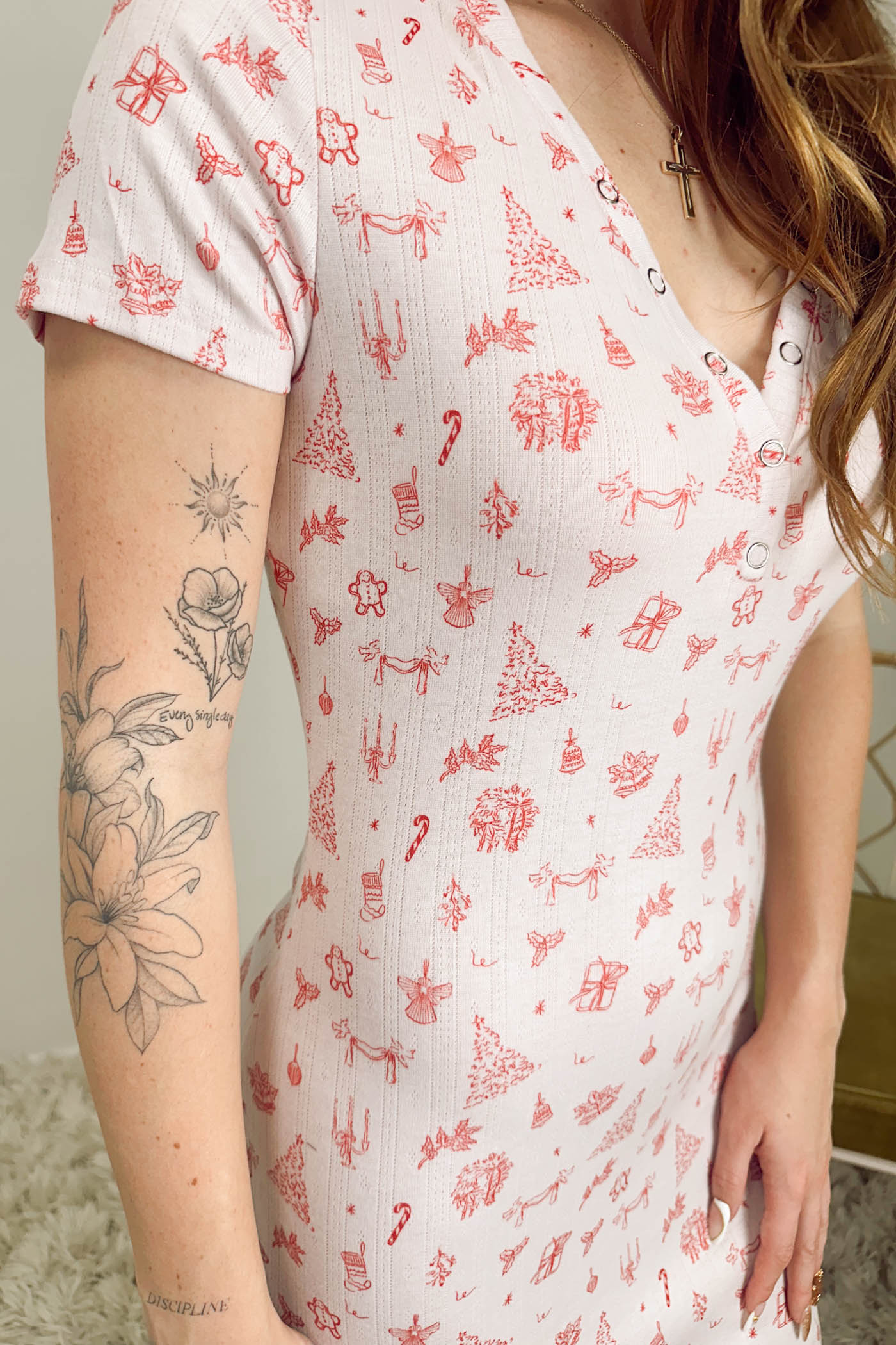 Person wearing a white dress with red patterns, standing against a neutral background.