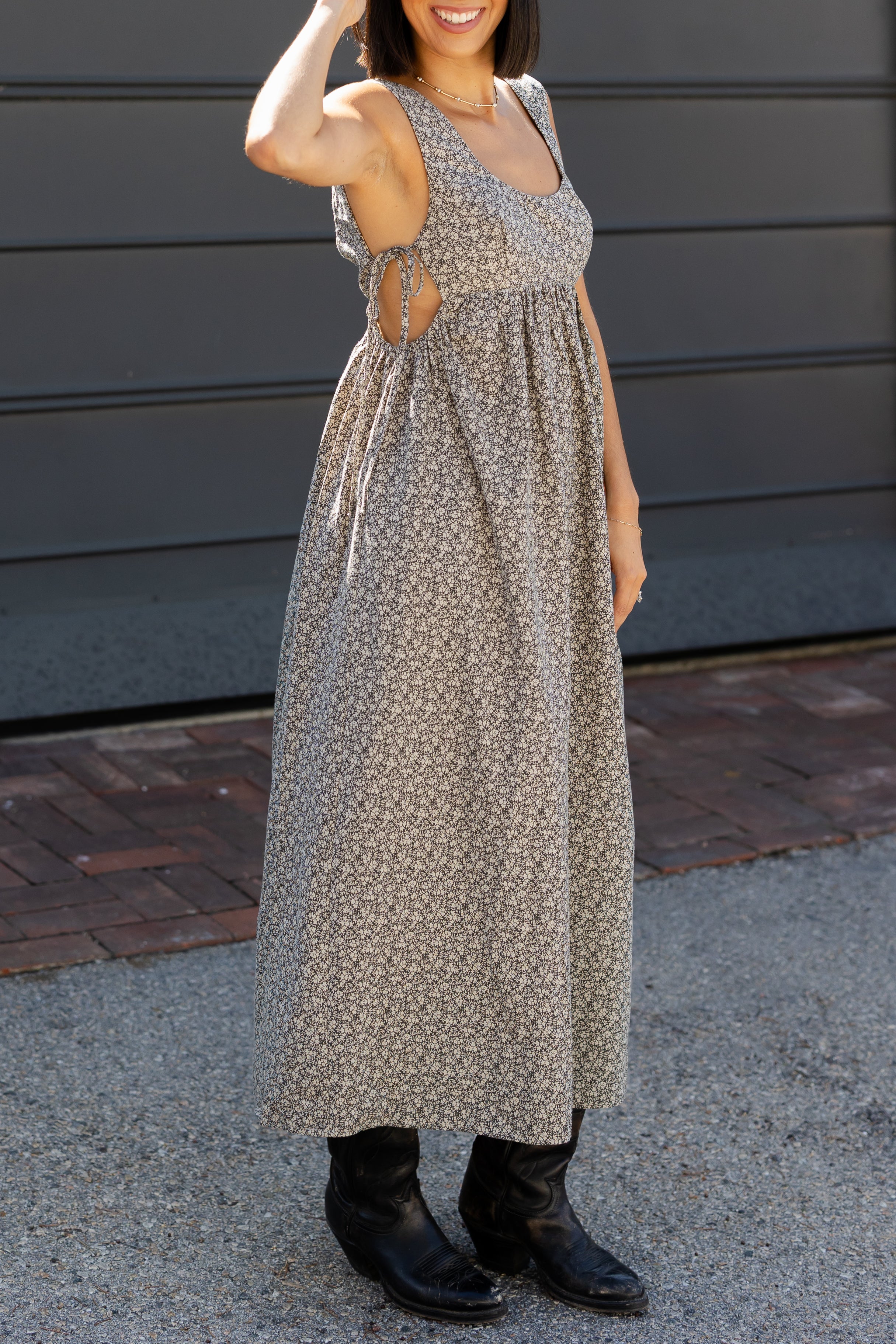 Woman wearing a long floral dress standing on a sidewalk.