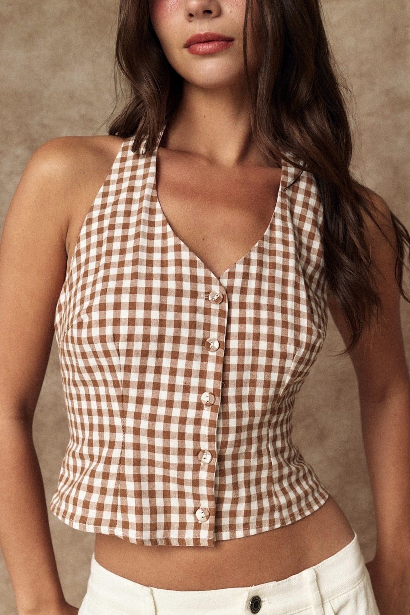 Woman wearing a brown and white checkered halter top against a beige background