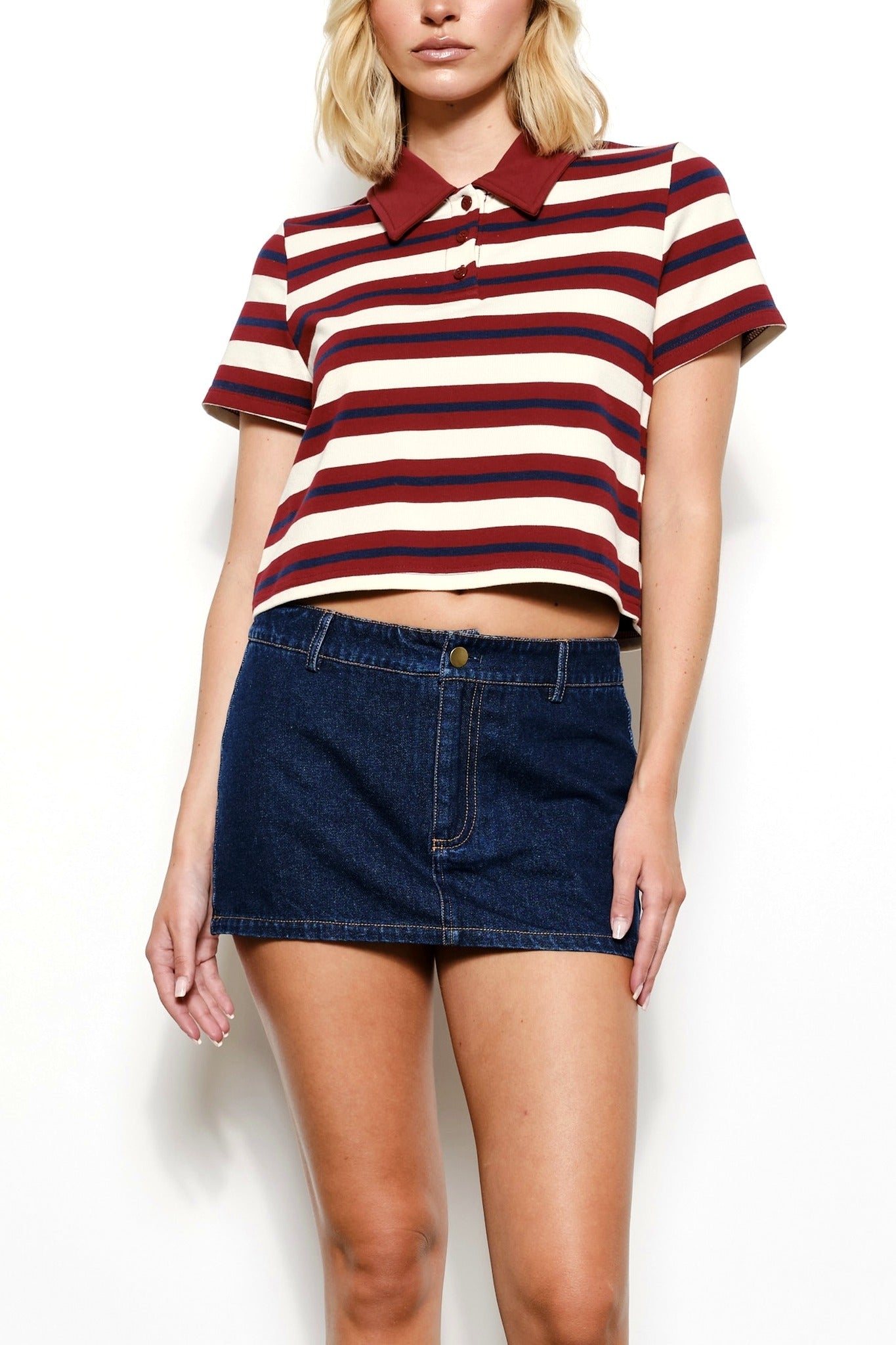 Woman wearing a striped polo shirt and denim skirt on a white background