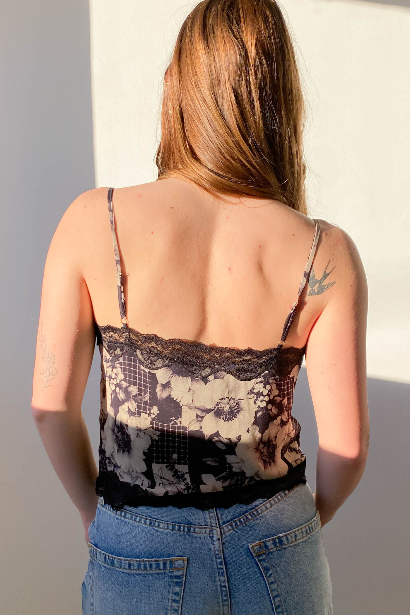 Person wearing a lace camisole and jeans against a neutral background