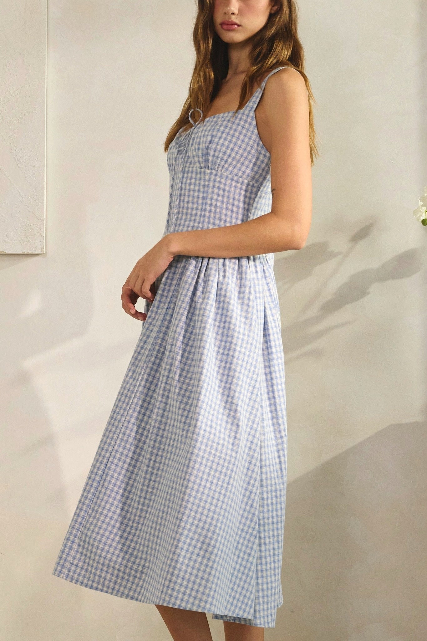 Woman wearing a blue and white checkered dress against a neutral background
