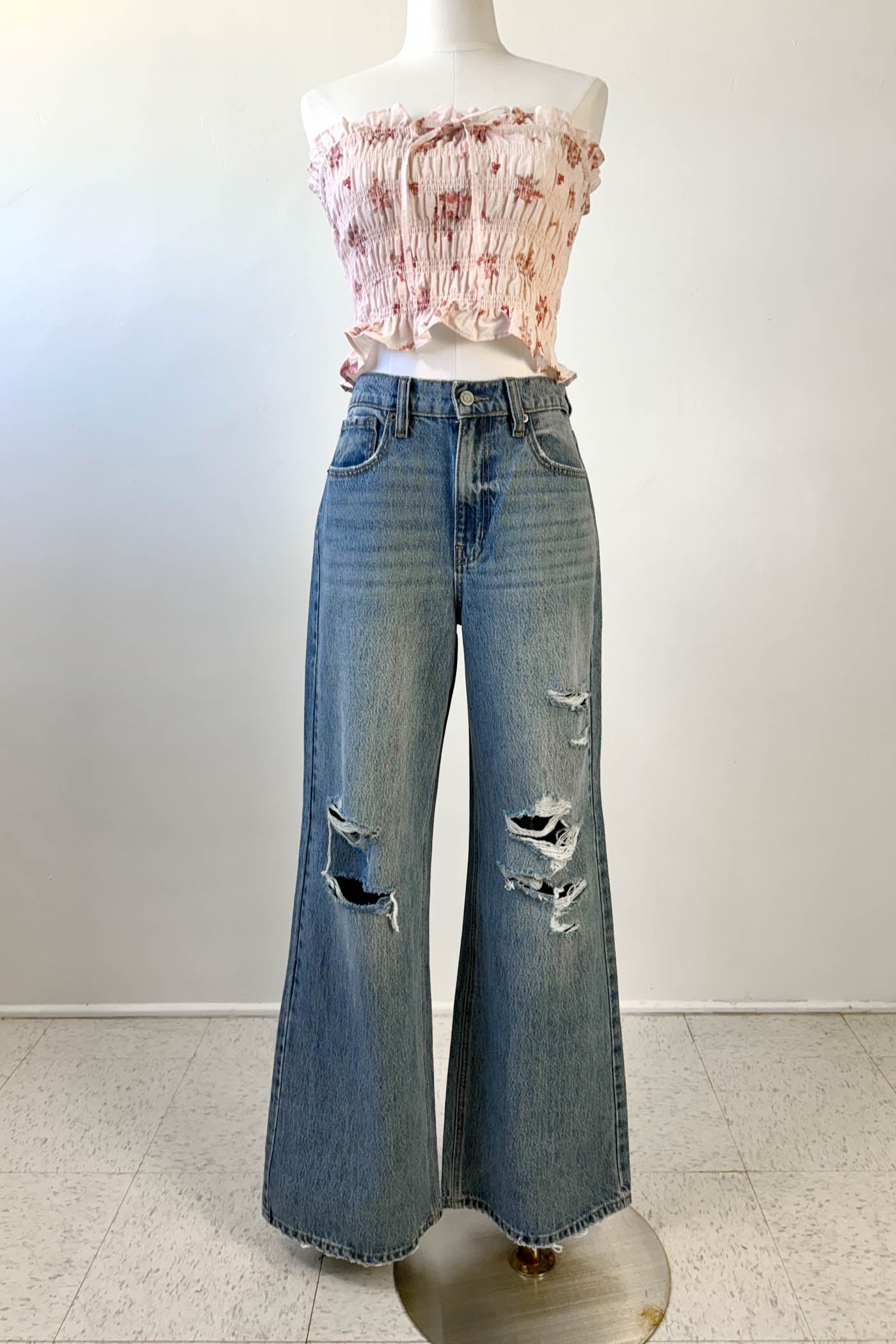 Mannequin wearing a floral top and distressed jeans on a white background