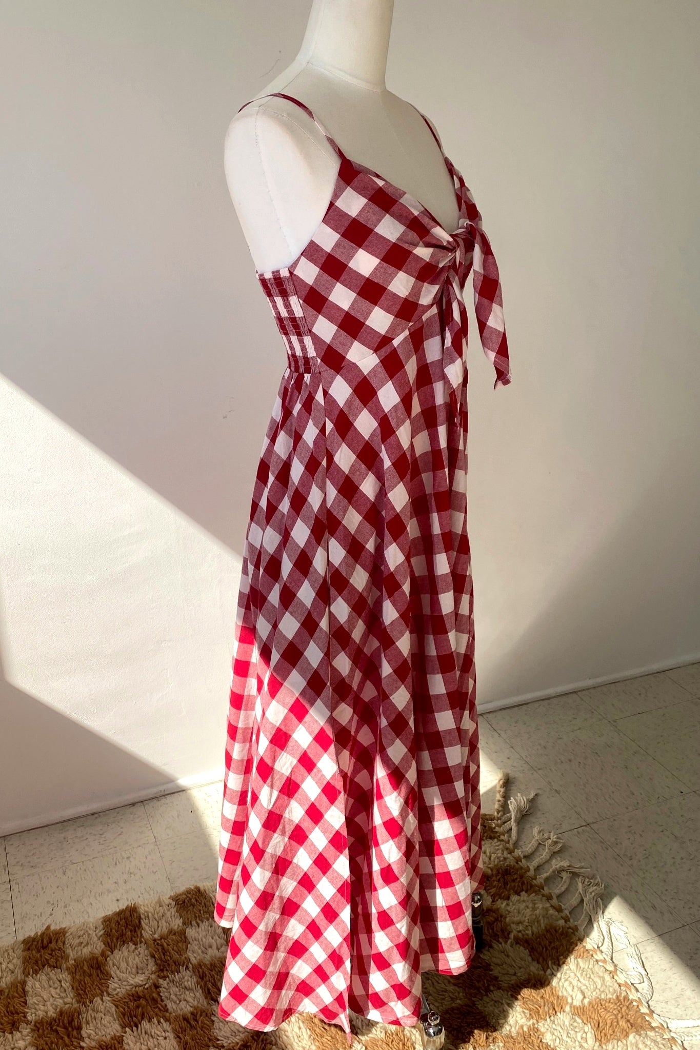 Red and white checkered dress on a mannequin against a plain background
