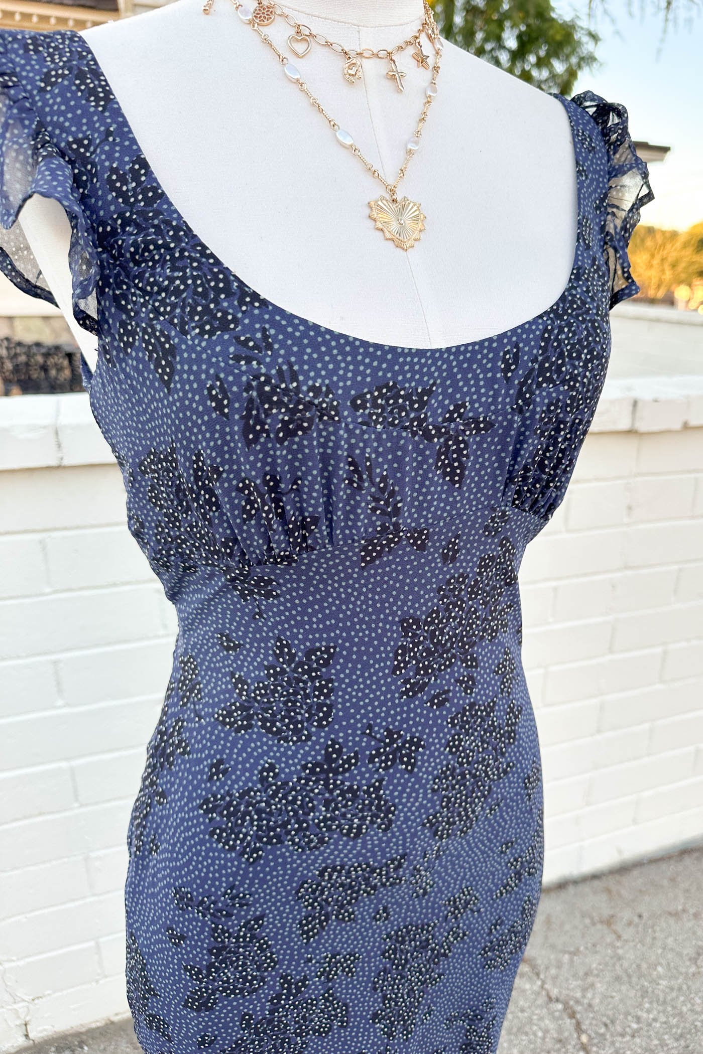 Blue beaded dress on a mannequin with a white brick wall background