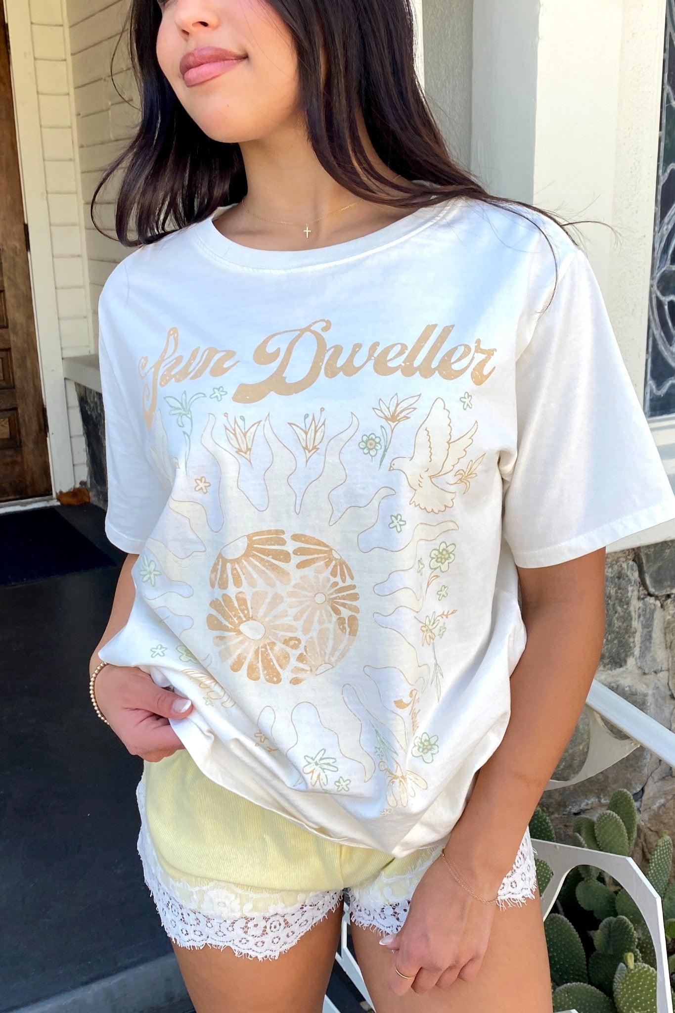 Person wearing a 'Juno Dwellers' t-shirt with floral designs outdoors.