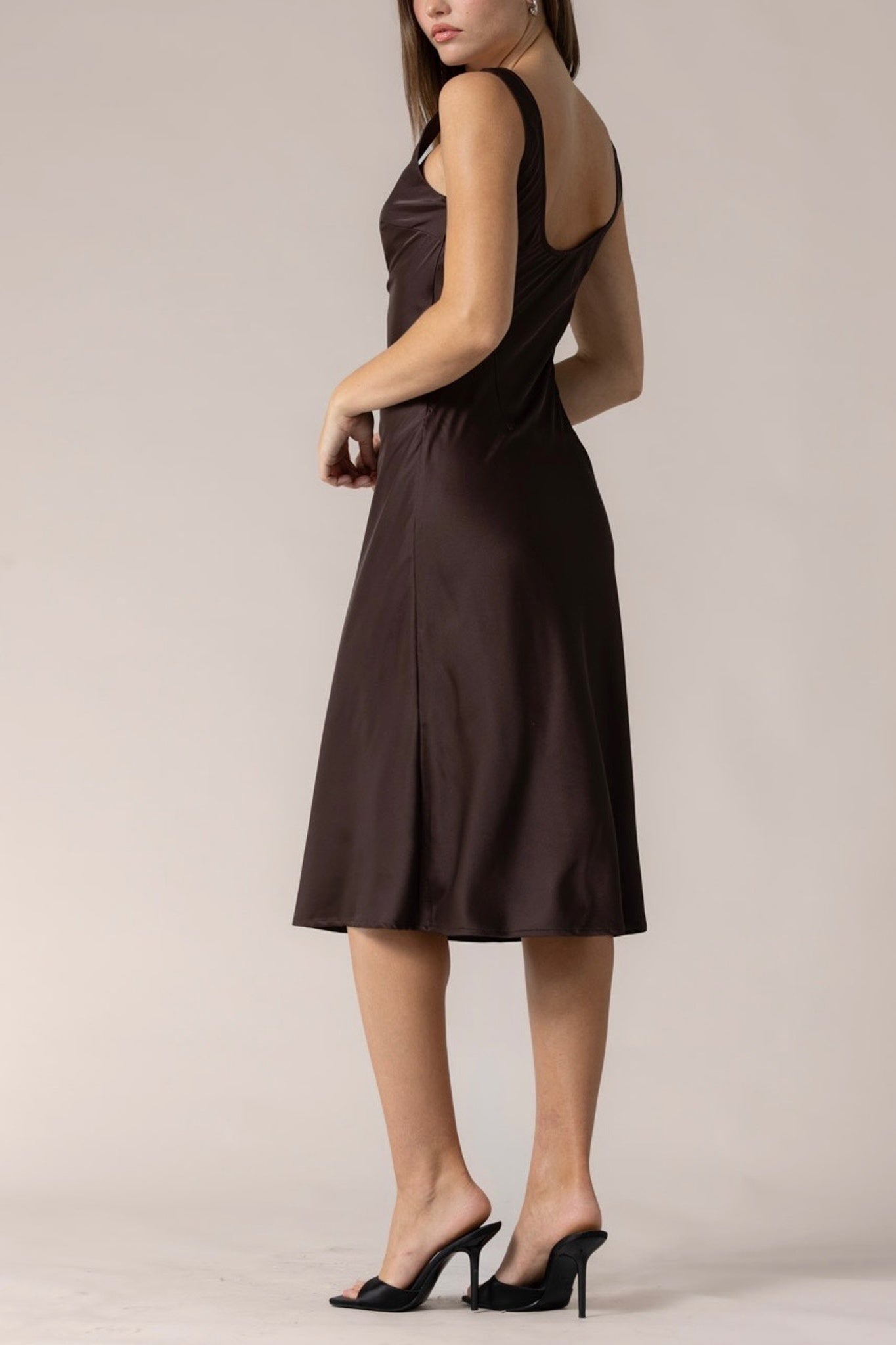 Woman wearing a brown dress against a plain background