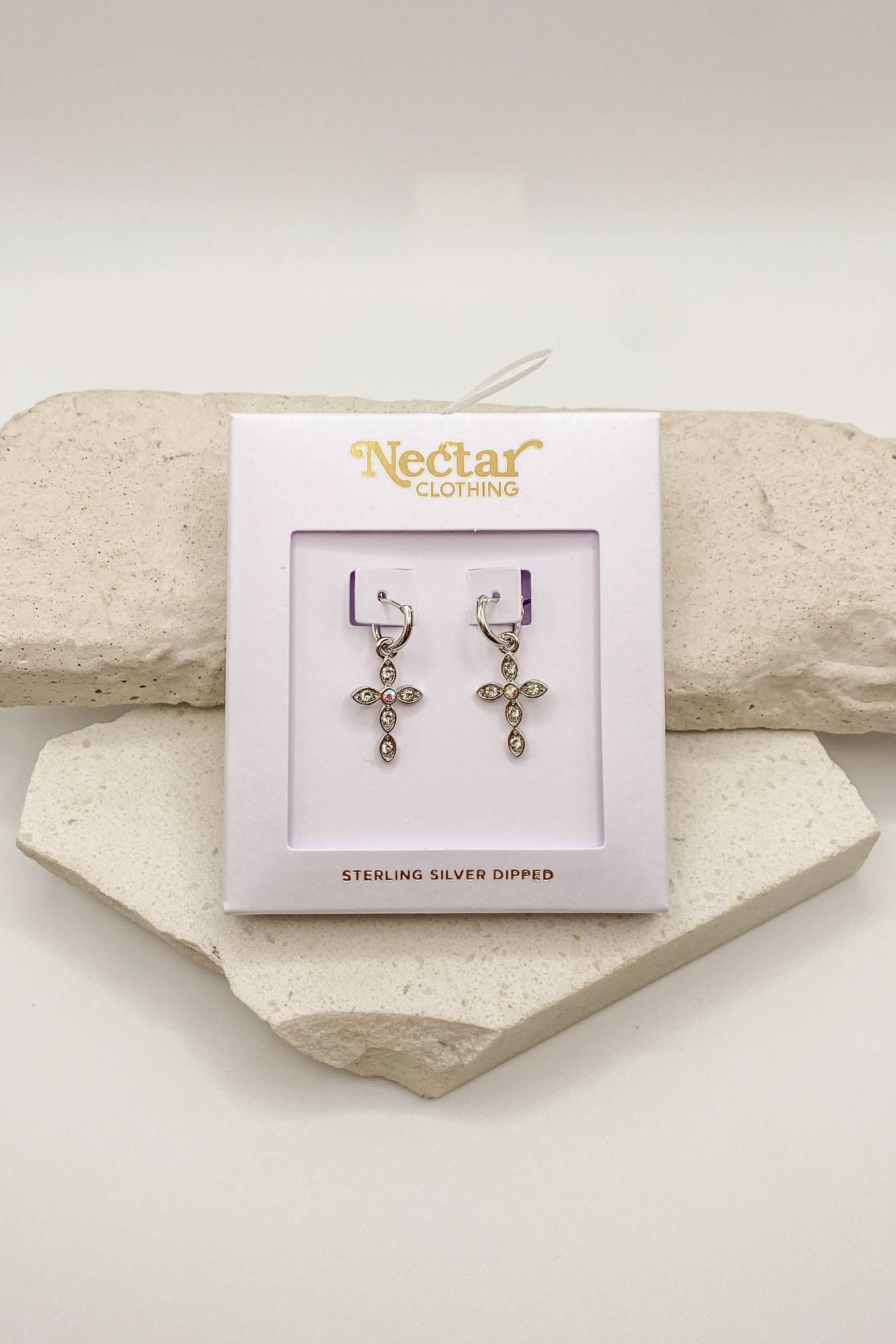 Pair of earrings on a Nectar Clothing branded card with stone background