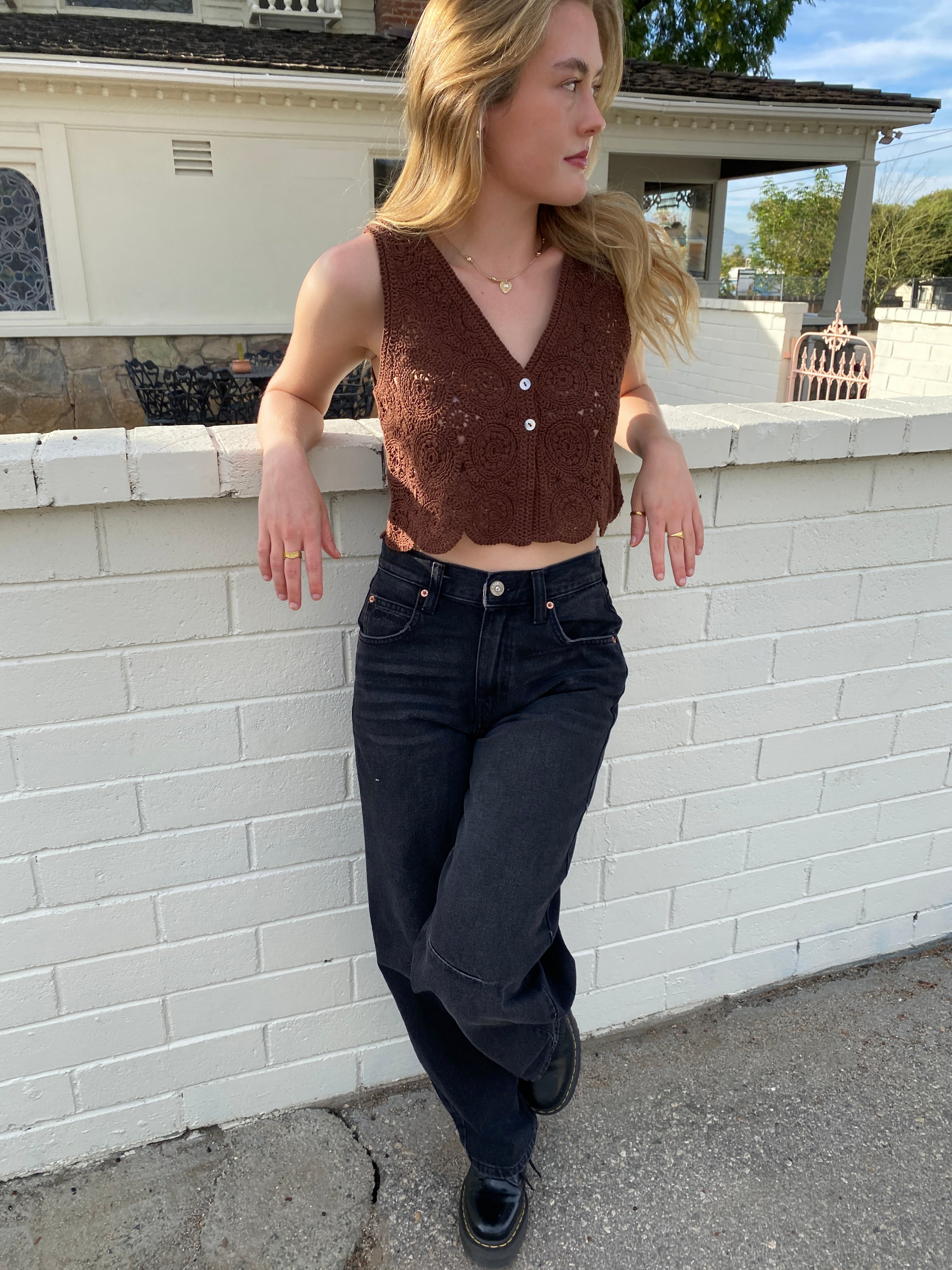 Person wearing a brown top and black pants on a sidewalk.