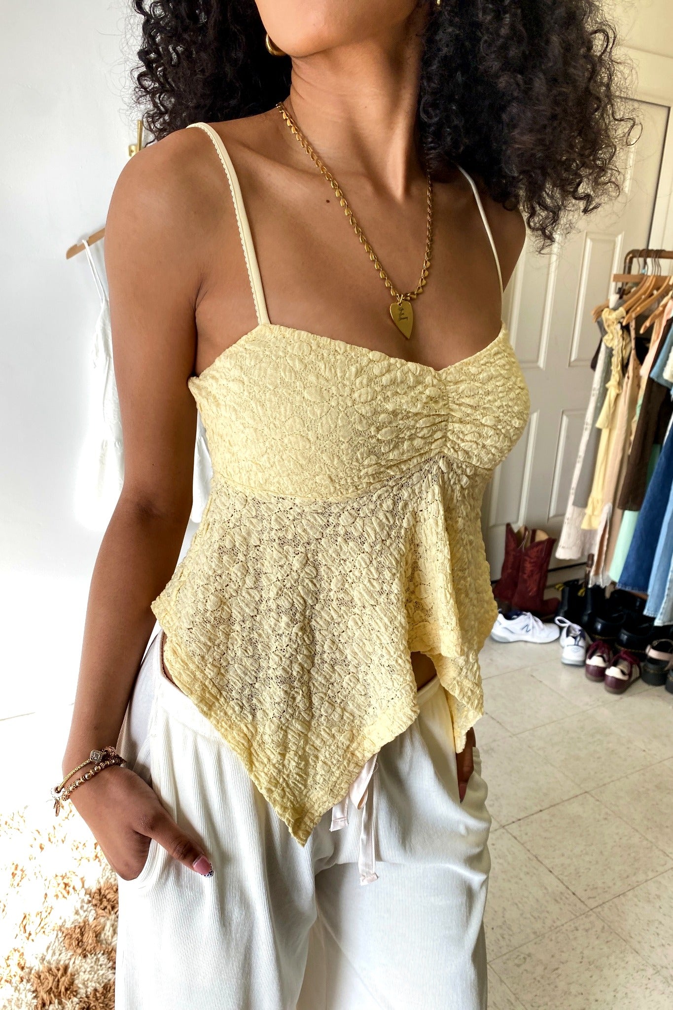Woman wearing a yellow lace top and white pants in an indoor setting.