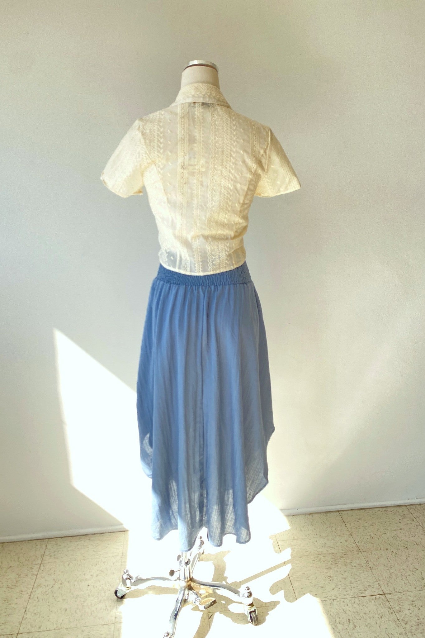 Mannequin wearing a white blouse and blue skirt against a plain background