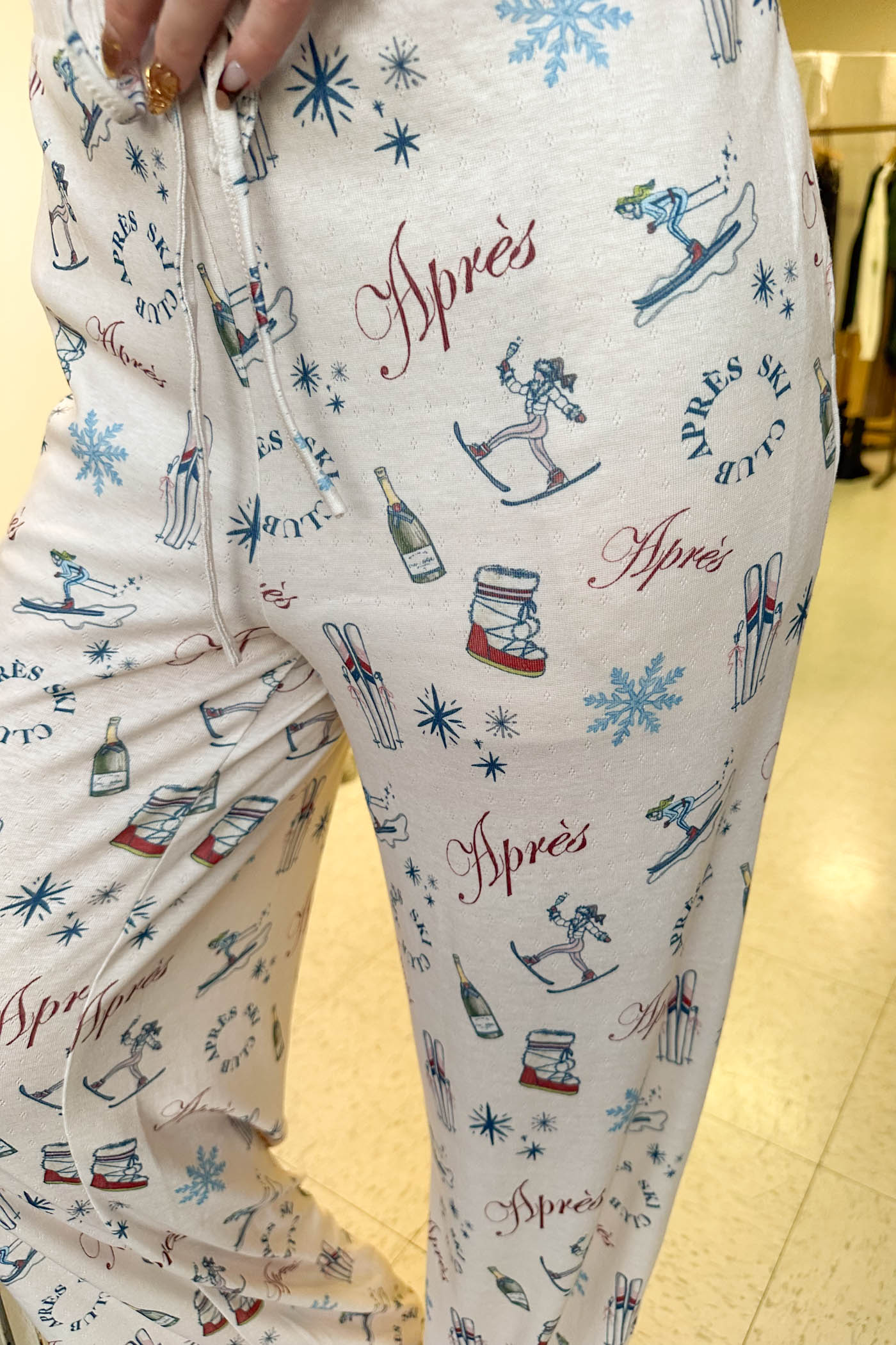 Close-up of a person wearing pajama pants with 'Apres' ski-themed print.