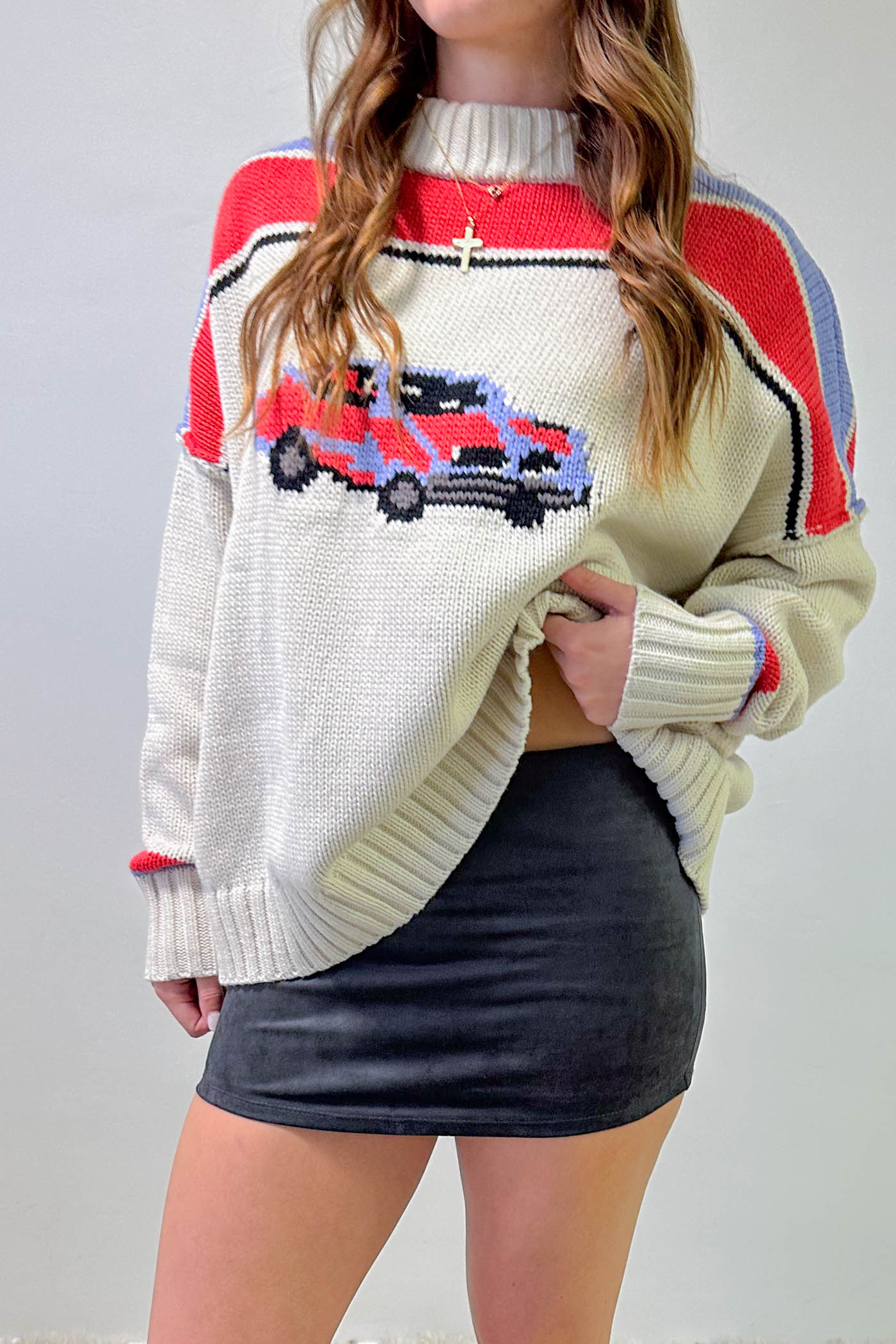 Person wearing a colorful sweater with a car design on a plain background