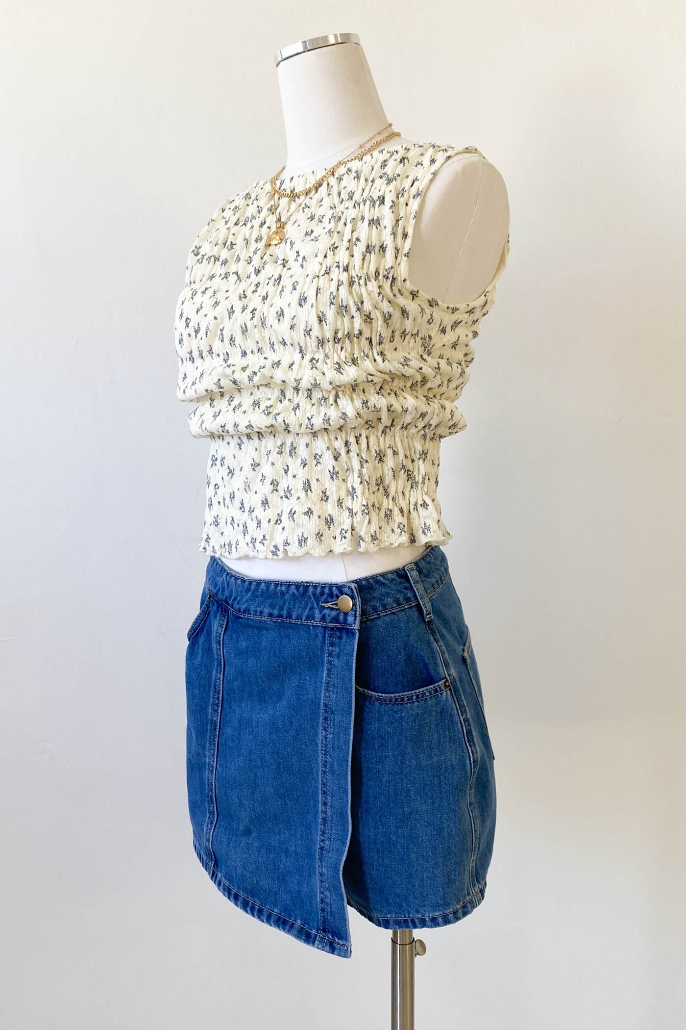 Mannequin wearing a floral top and blue denim skirt on a white background