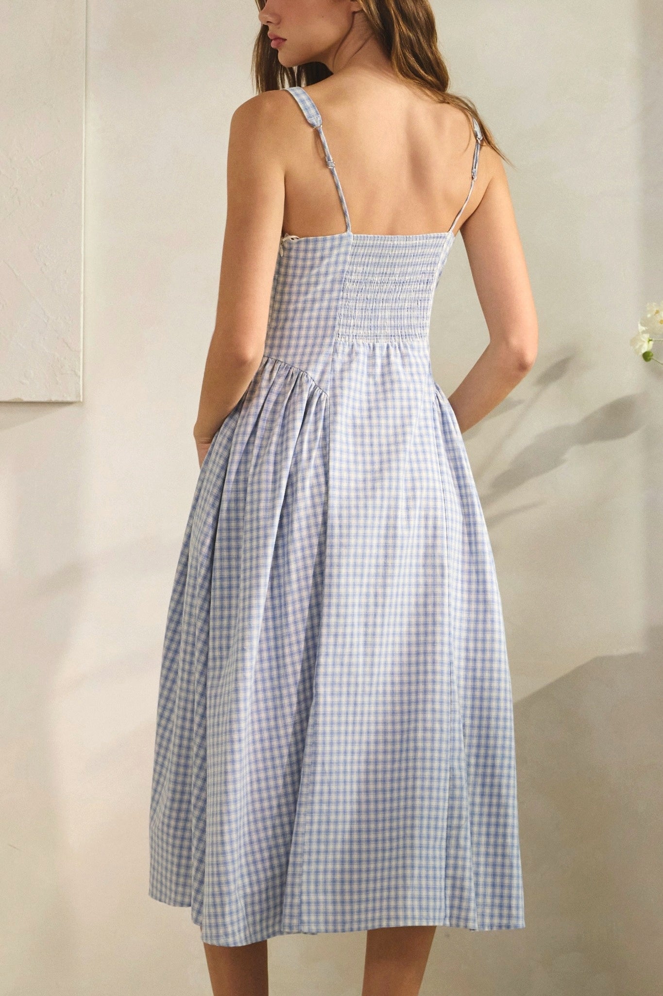 Woman wearing a blue and white checkered dress against a neutral background