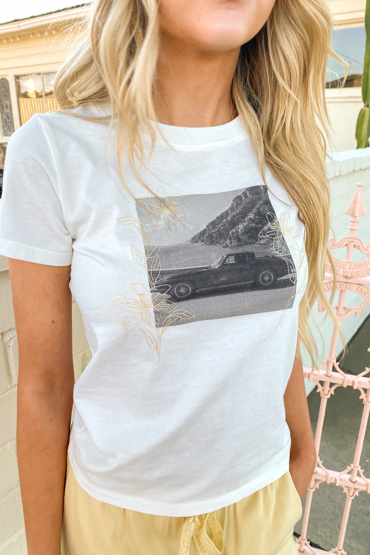 Person wearing a white t-shirt with a graphic design outdoors