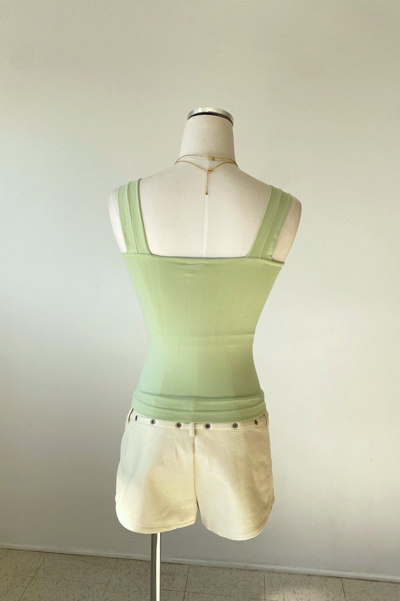 Mannequin wearing a light green tank top and white shorts against a plain background