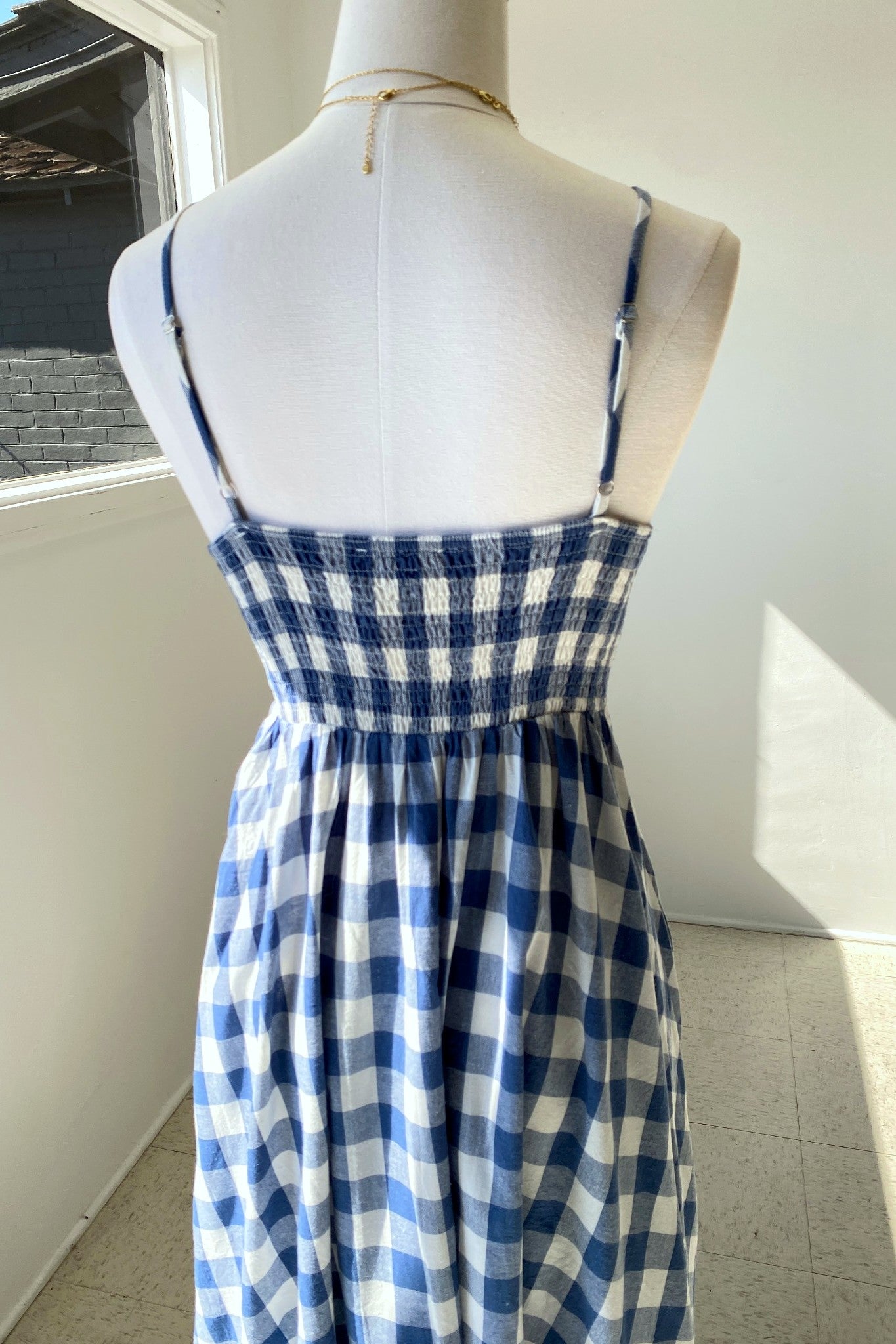 Blue and white checkered dress on a mannequin against a neutral background