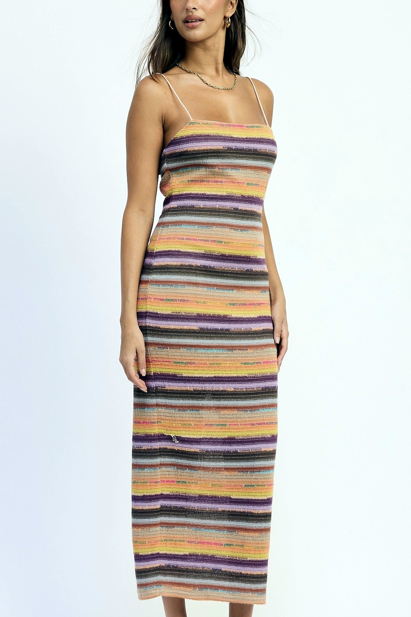Woman wearing a multicolored striped dress on a light gray background