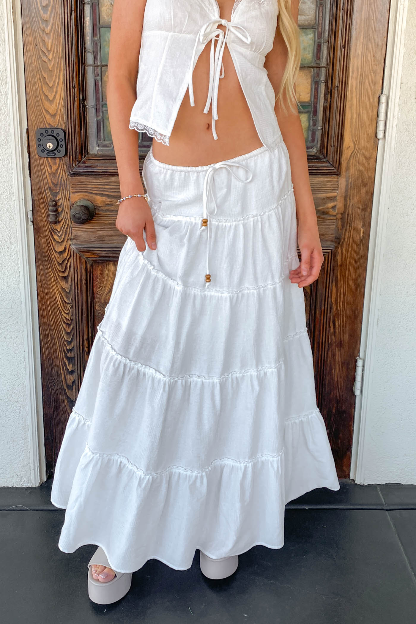 Woman wearing a white dress with a wooden door in the background