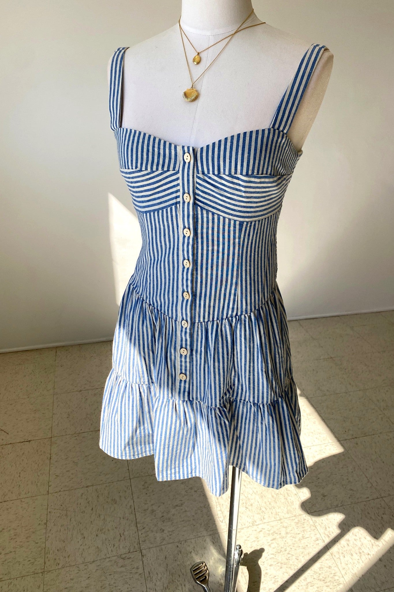 Blue and white striped dress on a mannequin against a plain background