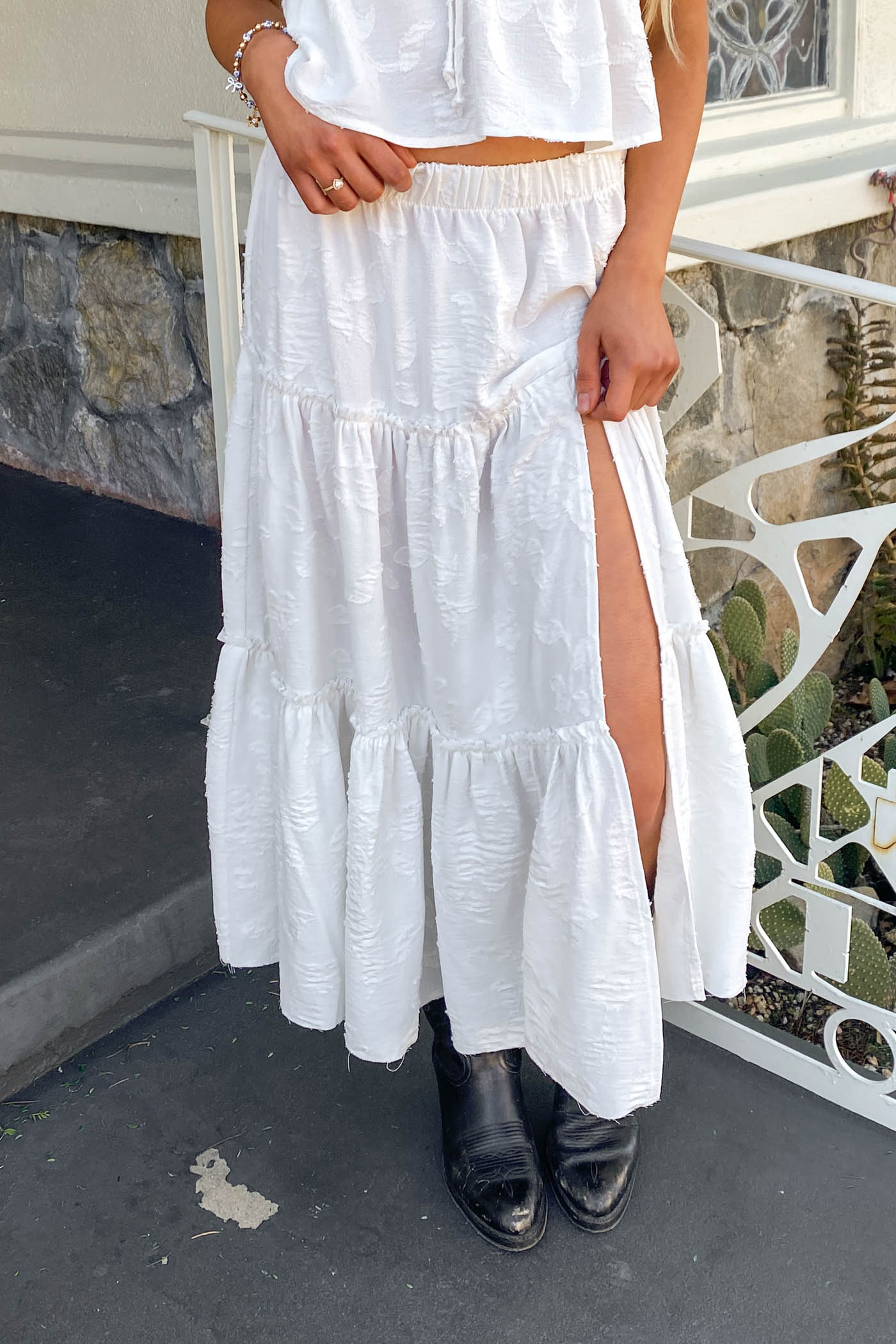 Person wearing a white dress with a slit on a stone pathway.