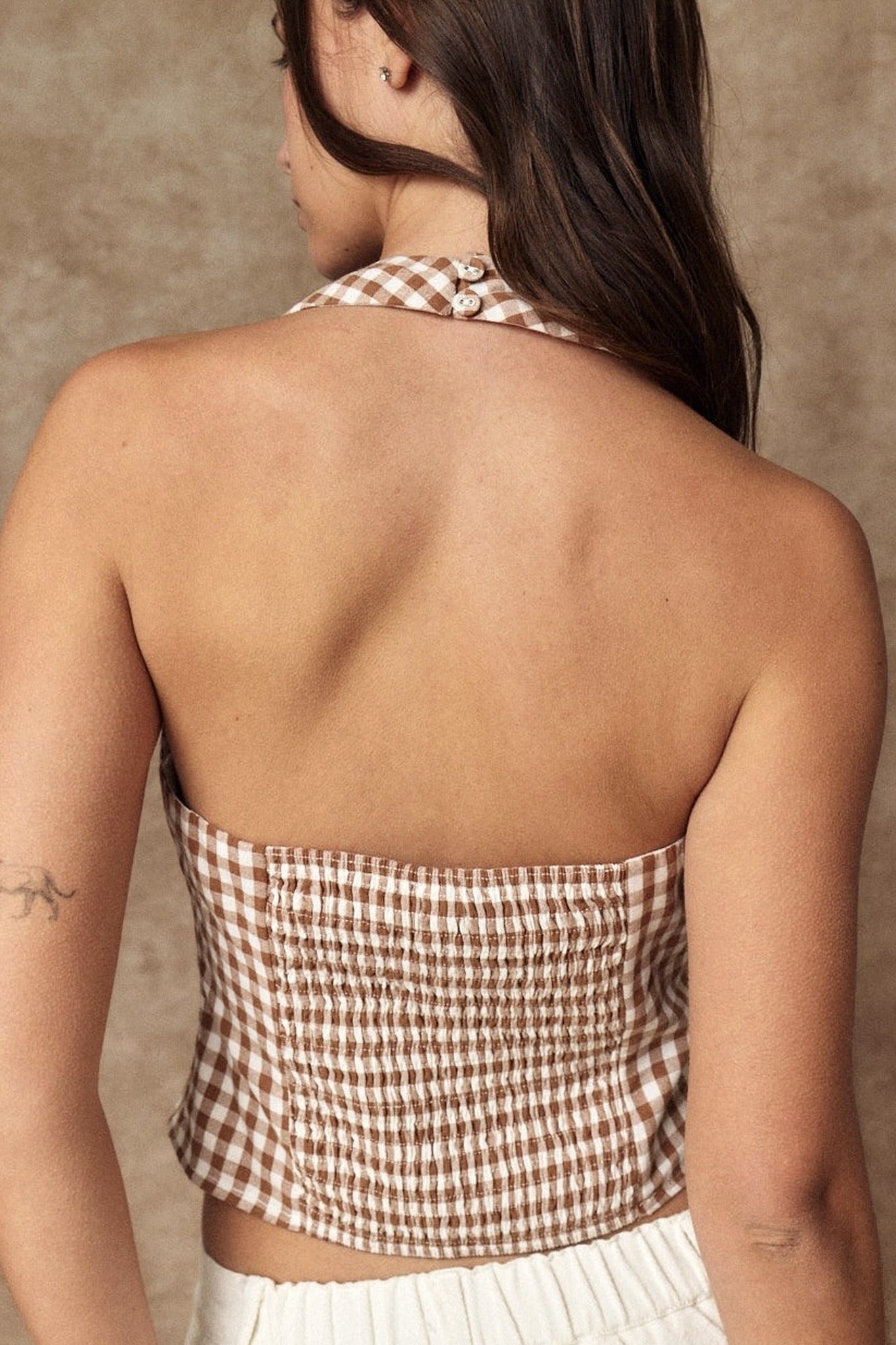 Woman wearing a checkered halter top against a neutral background