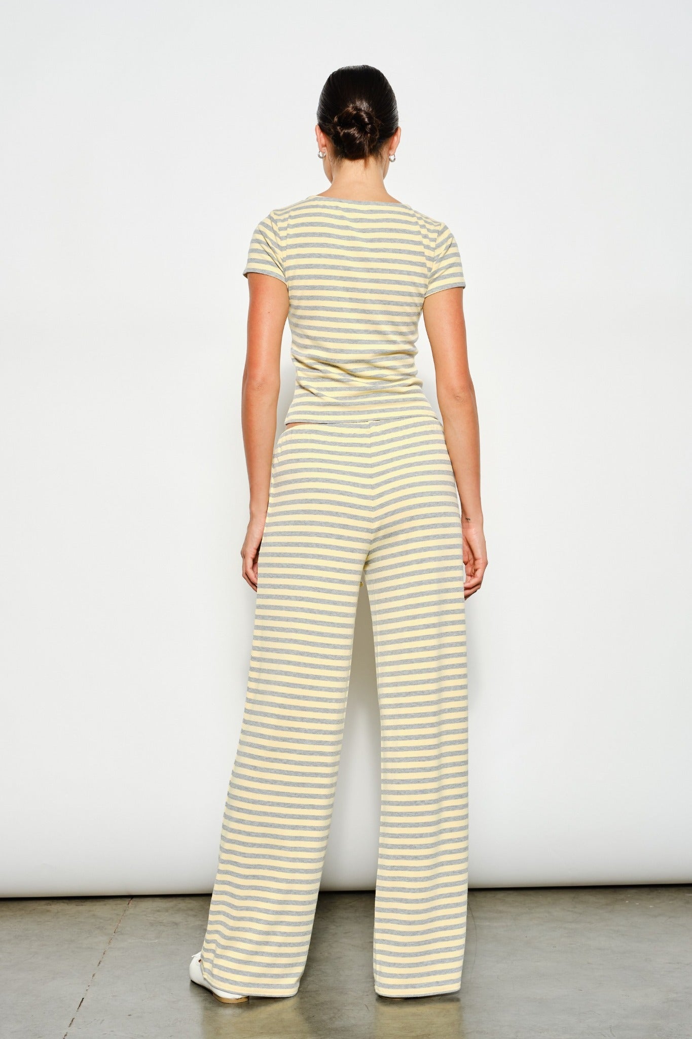 Woman wearing a yellow and white striped jumpsuit against a plain background