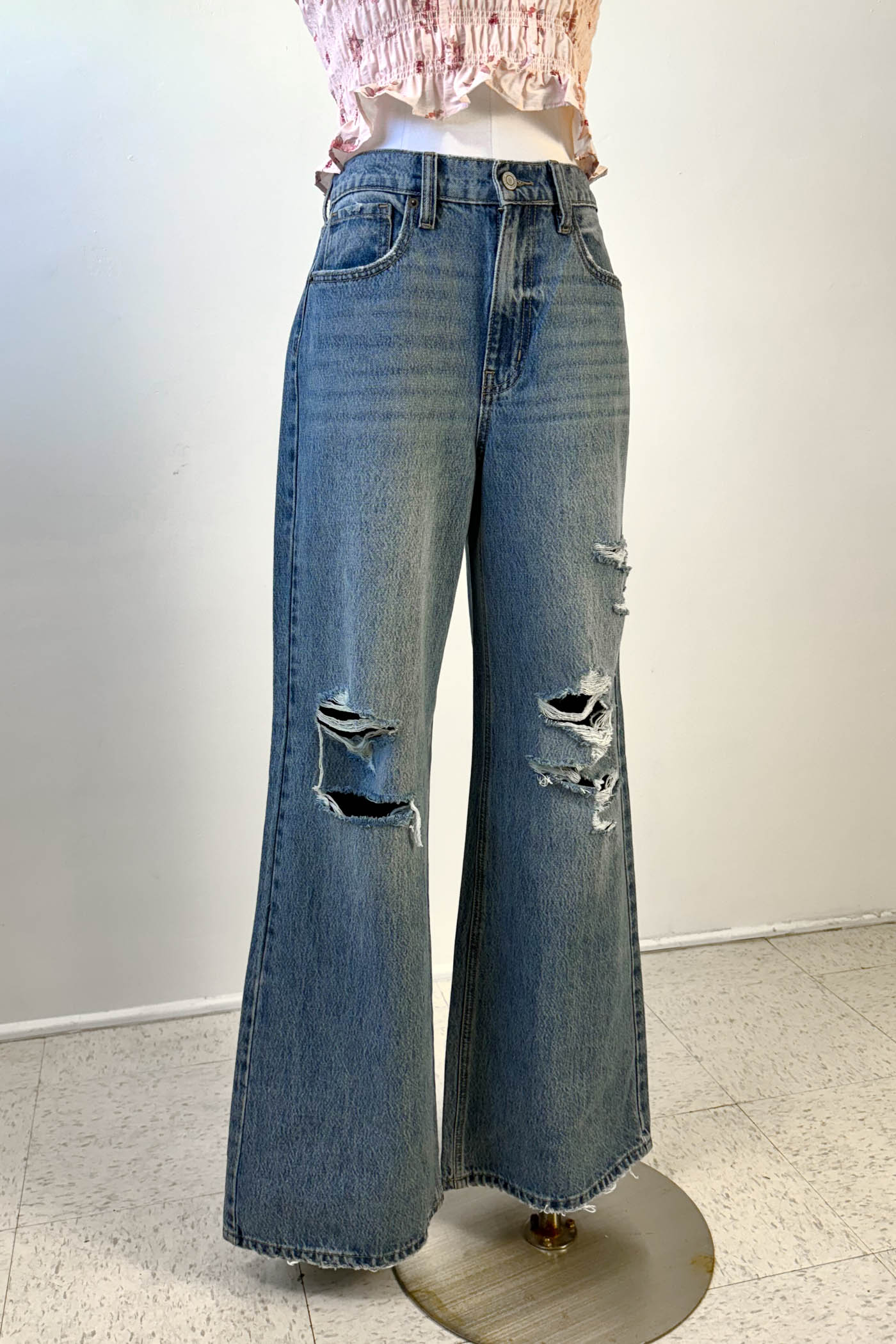 Distressed blue jeans on a mannequin against a white background