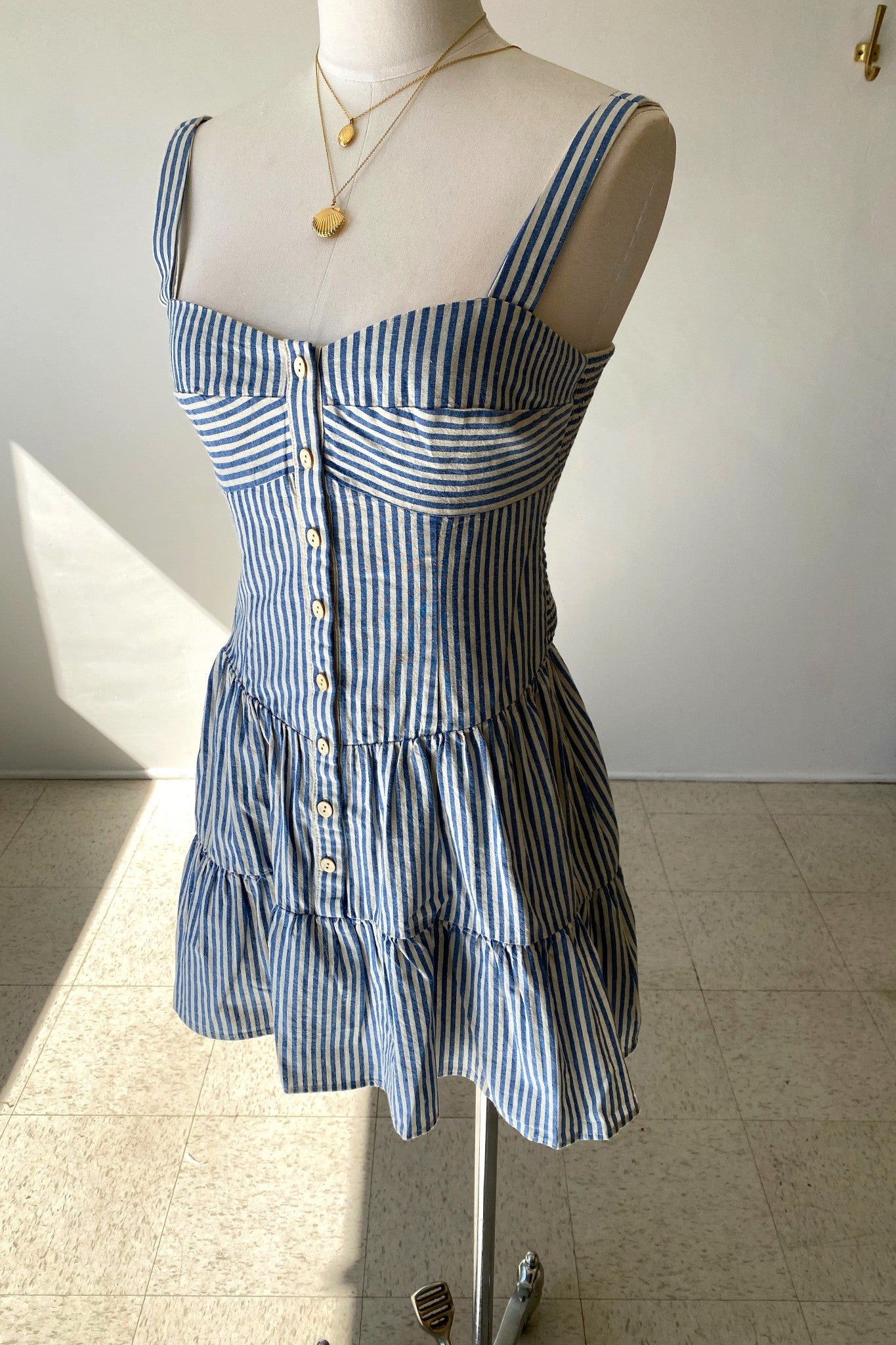 Blue and white striped dress on a mannequin against a plain background