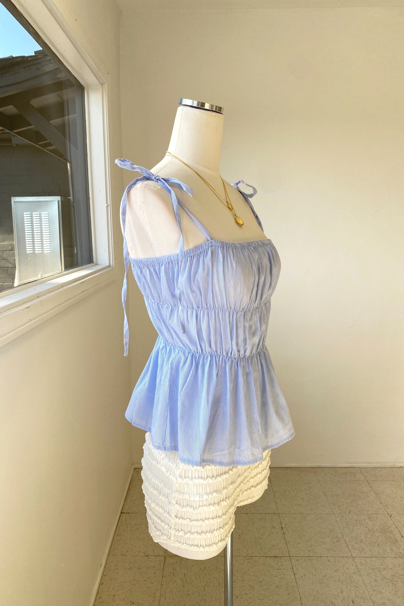Light blue sheer top on a mannequin against a neutral wall.