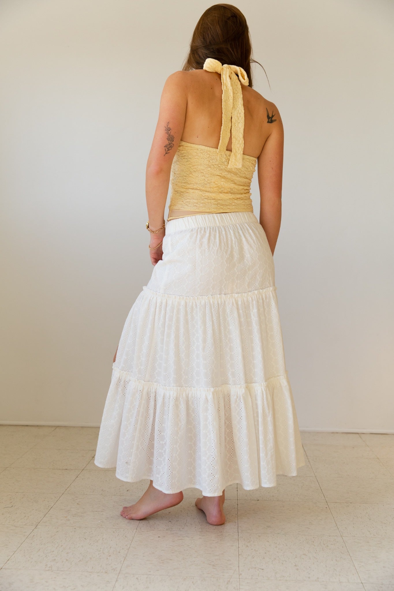 Woman wearing a yellow top and white skirt against a plain background