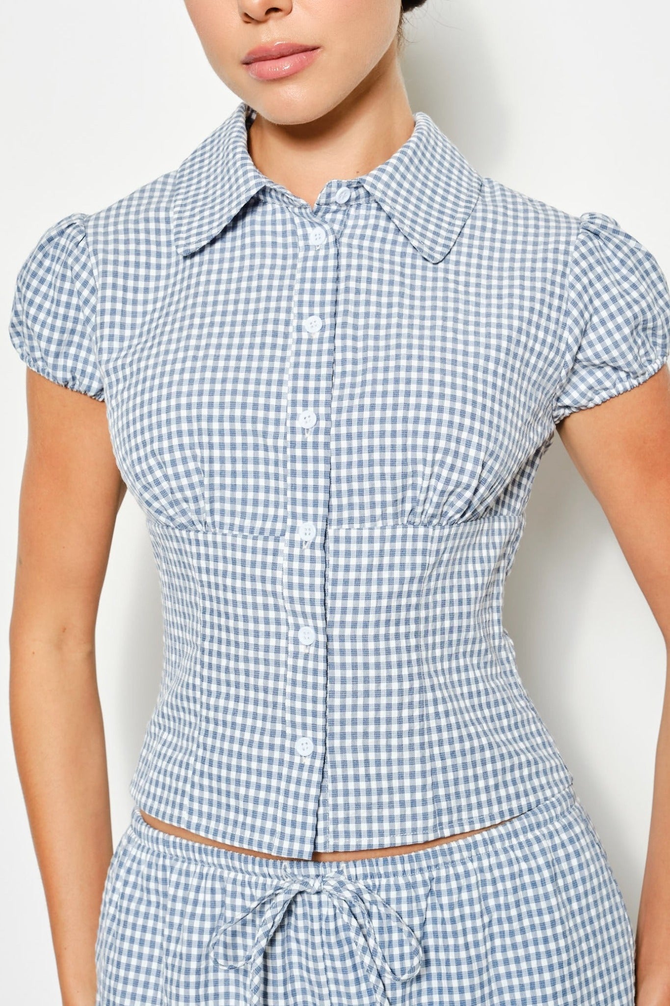 Person wearing a blue and white checkered dress against a plain background