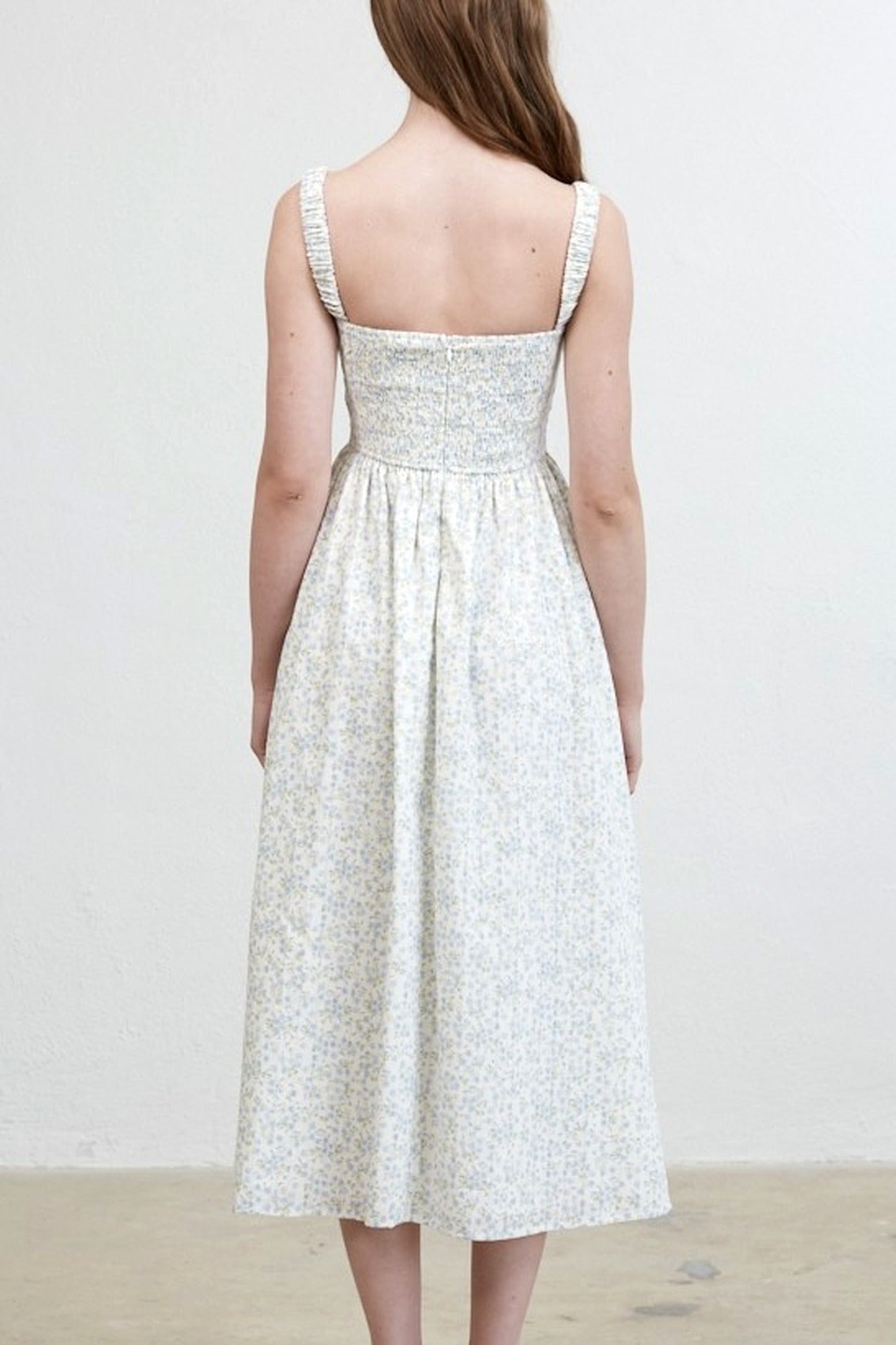 Woman wearing a white floral dress against a plain background