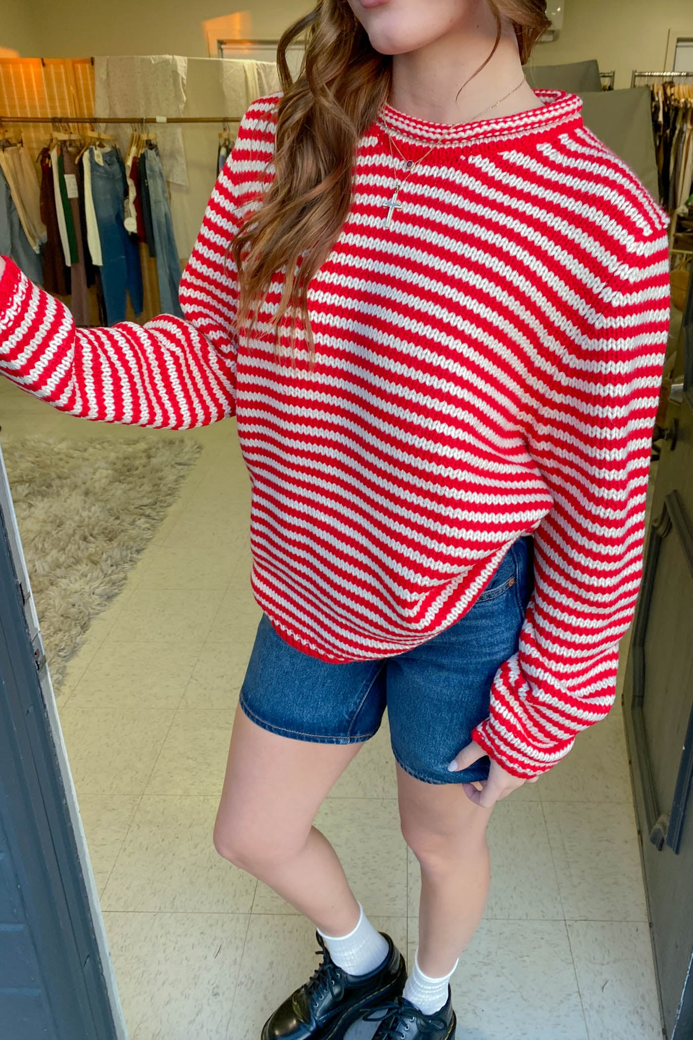 Person wearing a red and white striped sweater and denim shorts in a store setting.