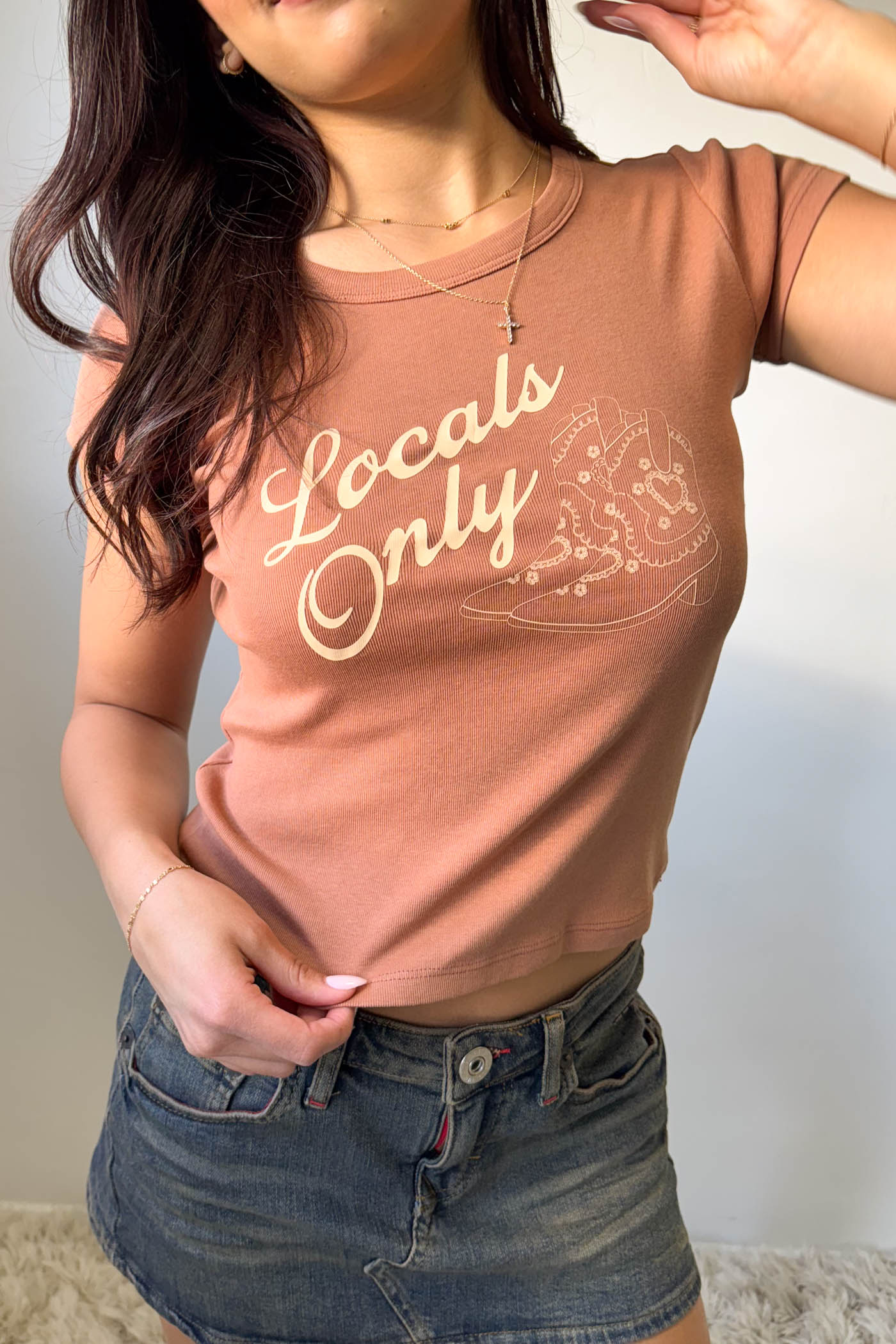 Person wearing a brown t-shirt with 'Locals Only' text and graphic.
