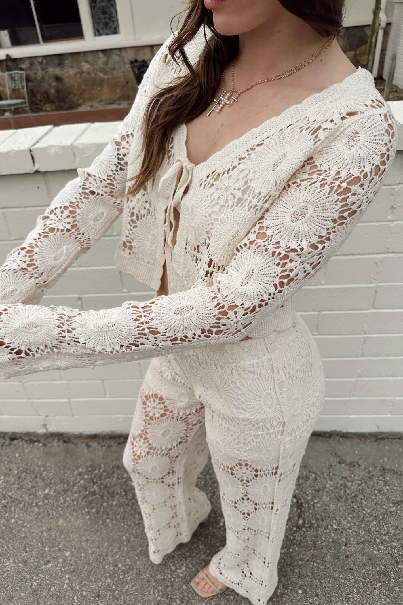Person wearing a white lace outfit standing outdoors.