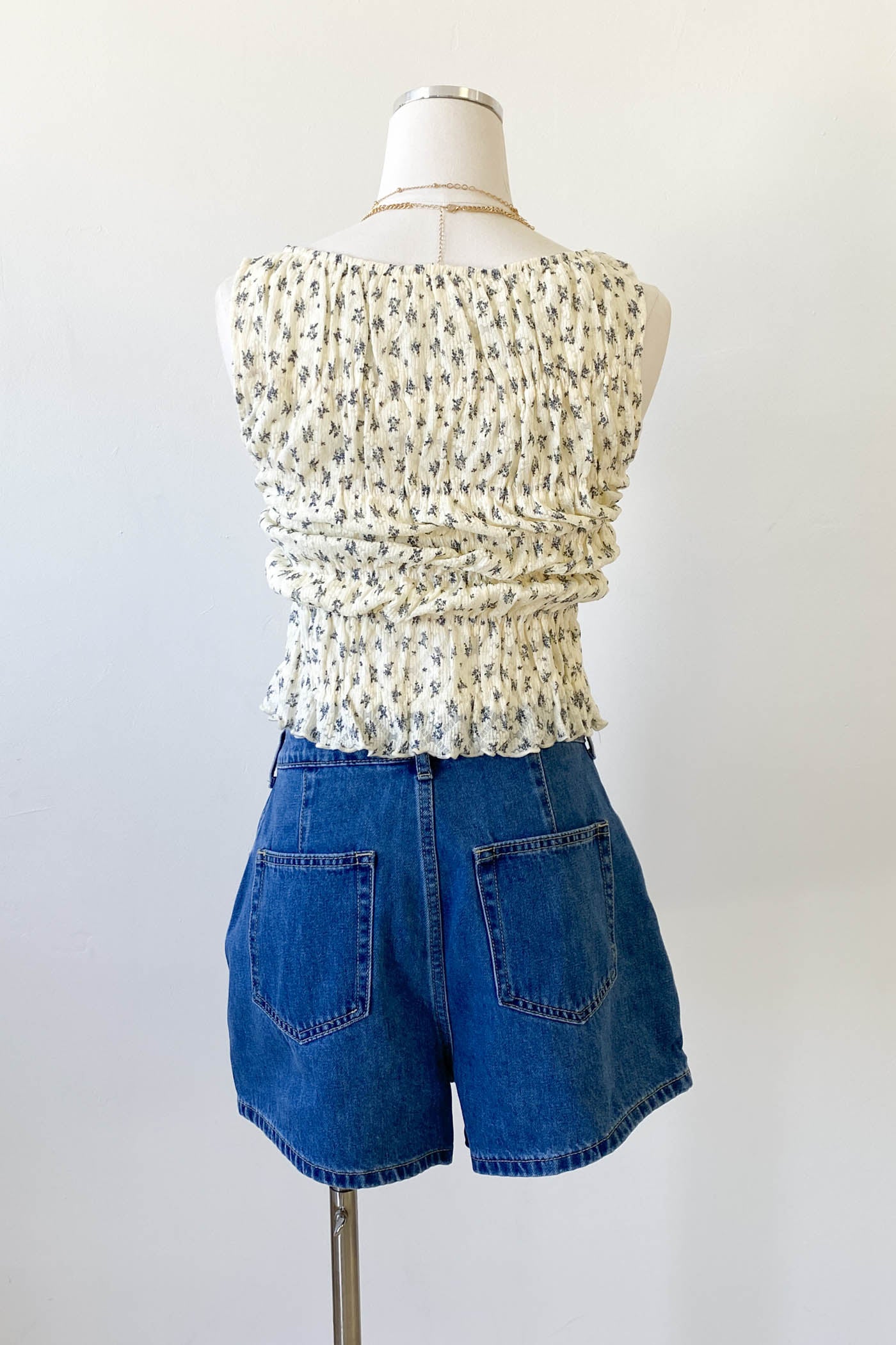 Mannequin wearing a white floral top and blue shorts on a white background