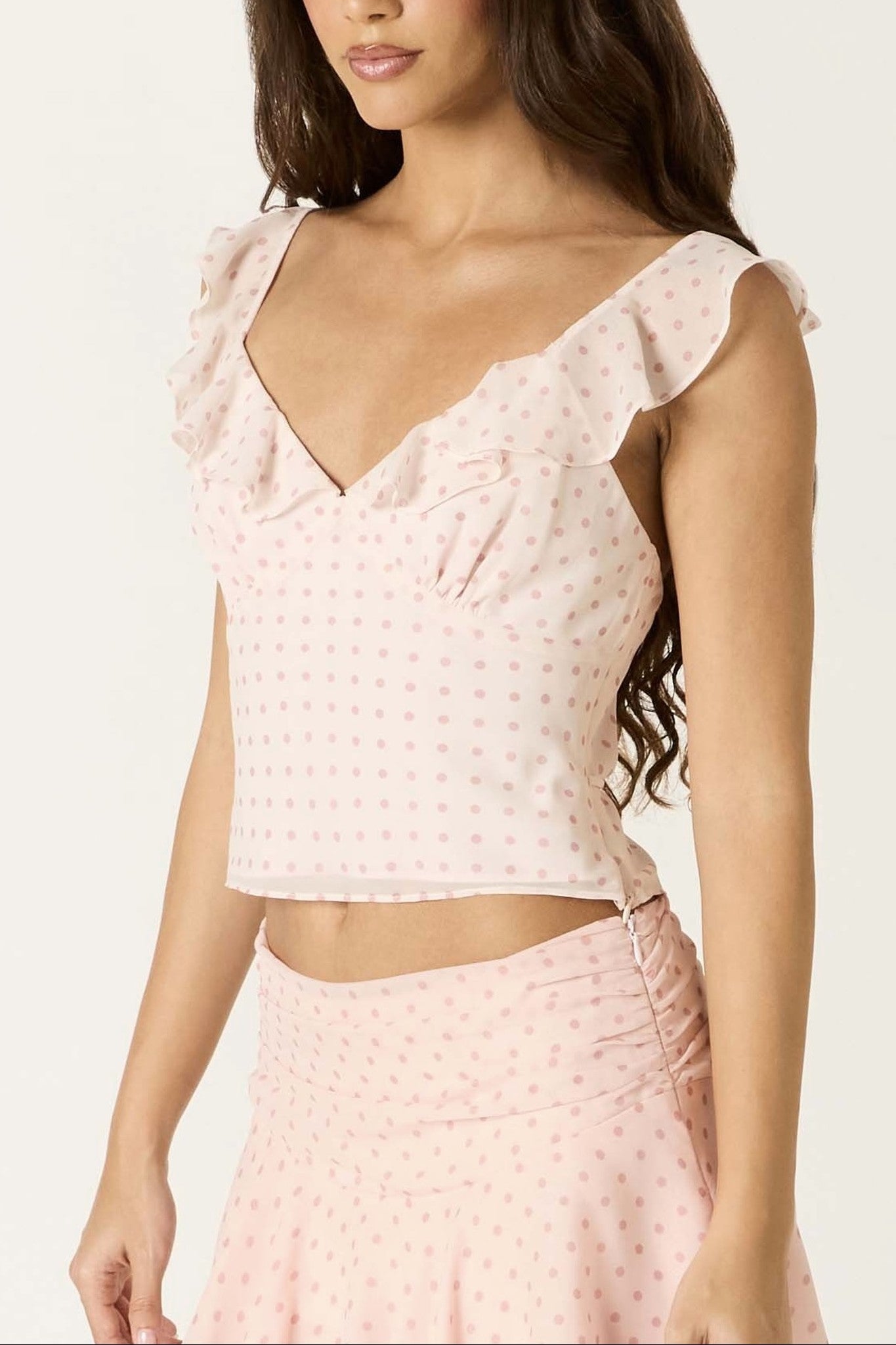 Woman wearing a pink polka dot top and skirt on a white background